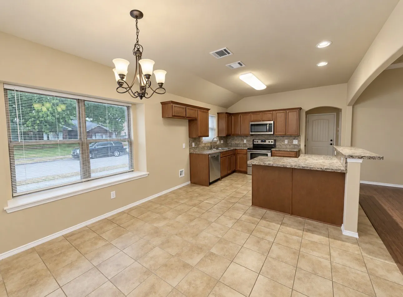 Kitchen featuring wood cabinetry, stainless steel appliances, granite countertops, and tile flooring