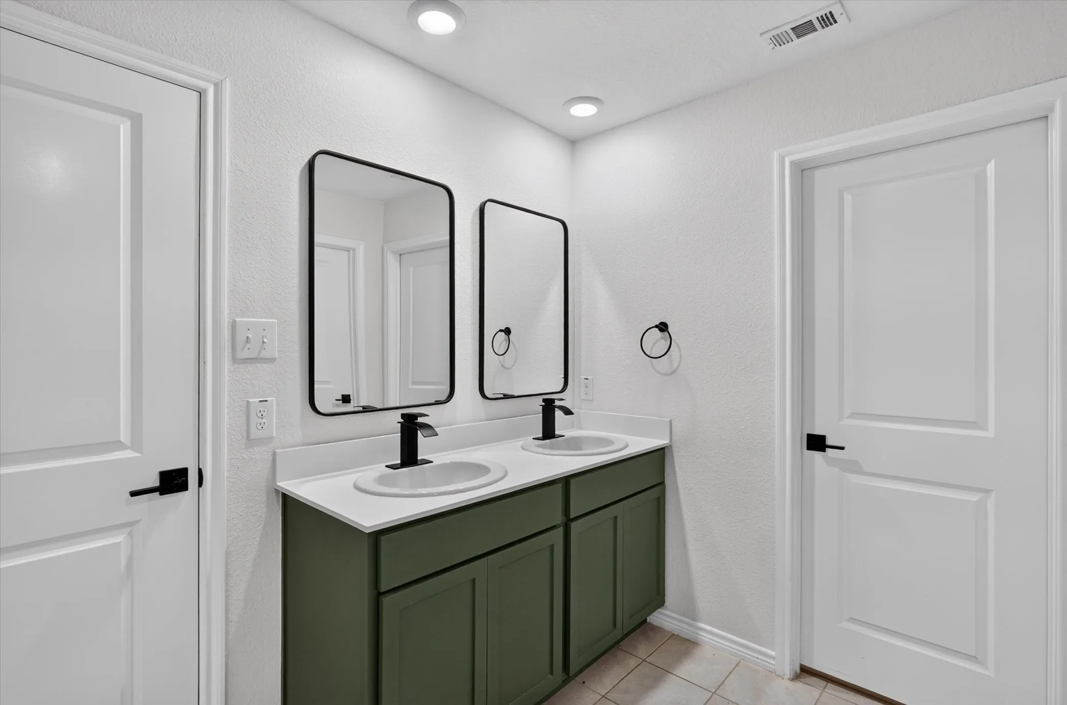 Dual vanity with green cabinetry, white countertops, and matte black fixtures