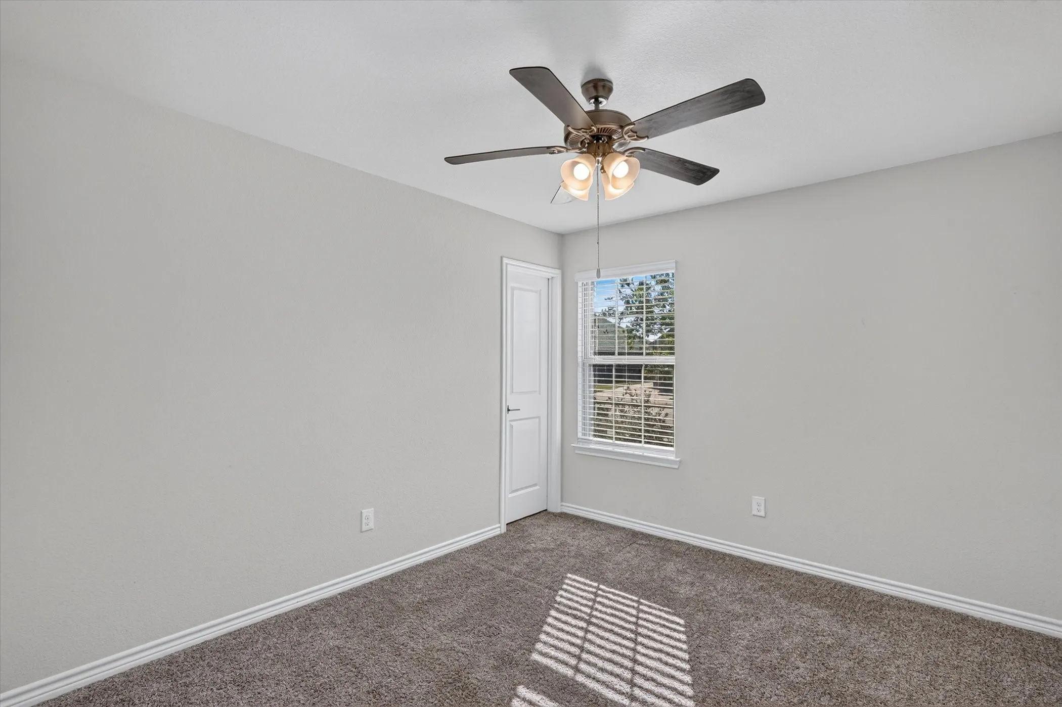 Ceiling fan with integrated lighting, window with blinds, light gray wall finish, white trim, and carpeted flooring