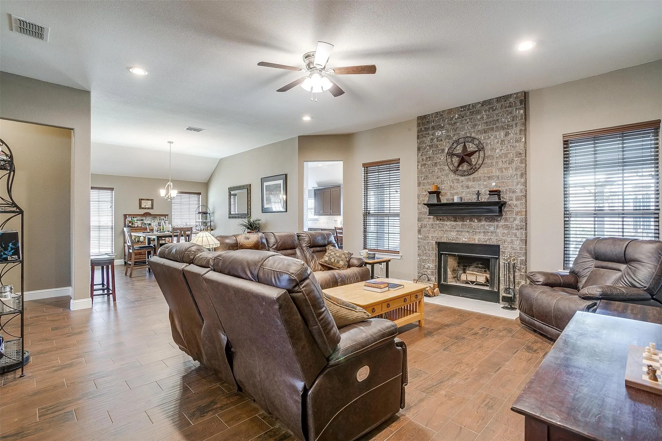 Living area featuring wood-finish flooring, a brick-faced fireplace with a mantel, recessed lighting, and a ceiling fan