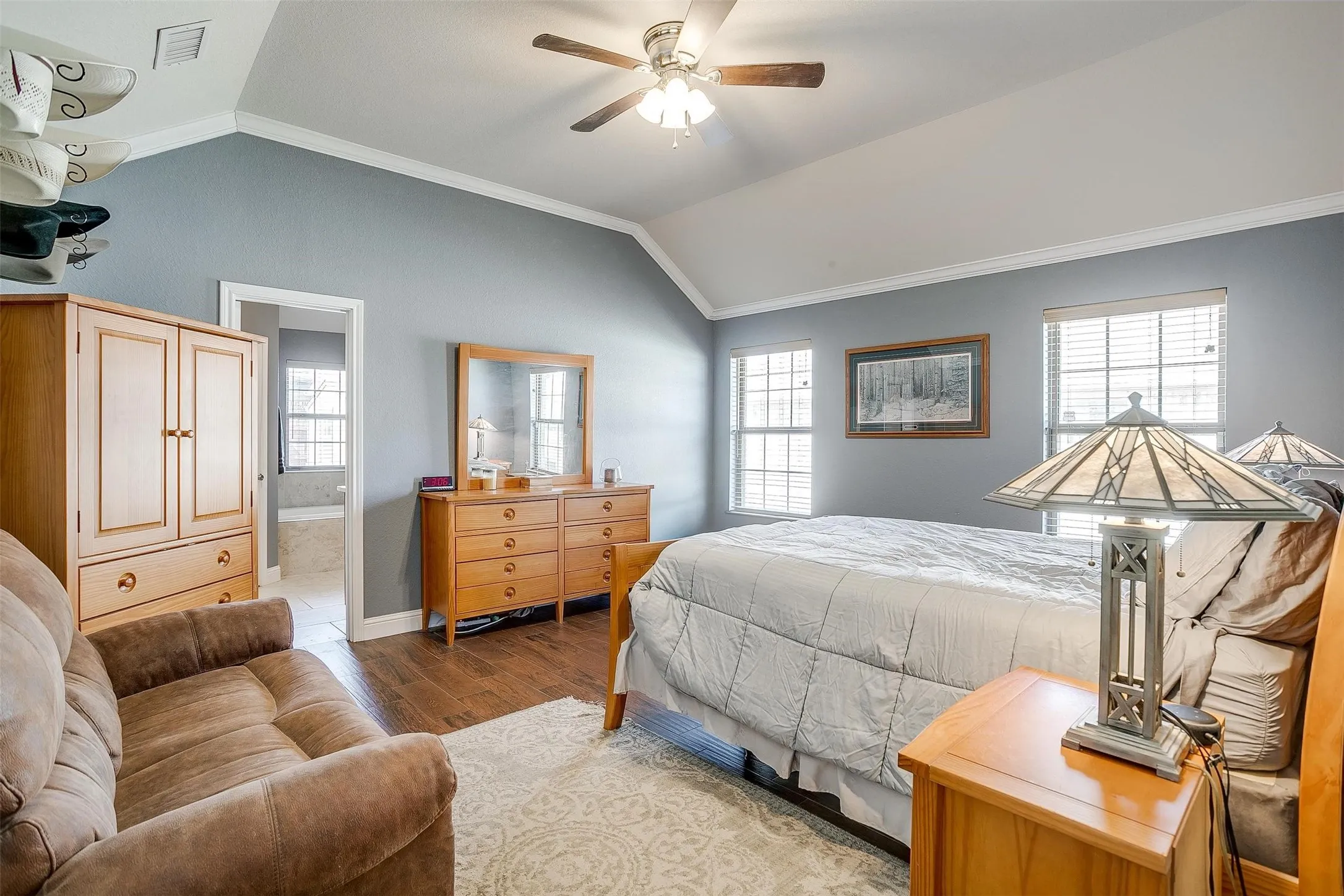 Vaulted ceiling with a ceiling fan, dual windows, and wood-finish flooring