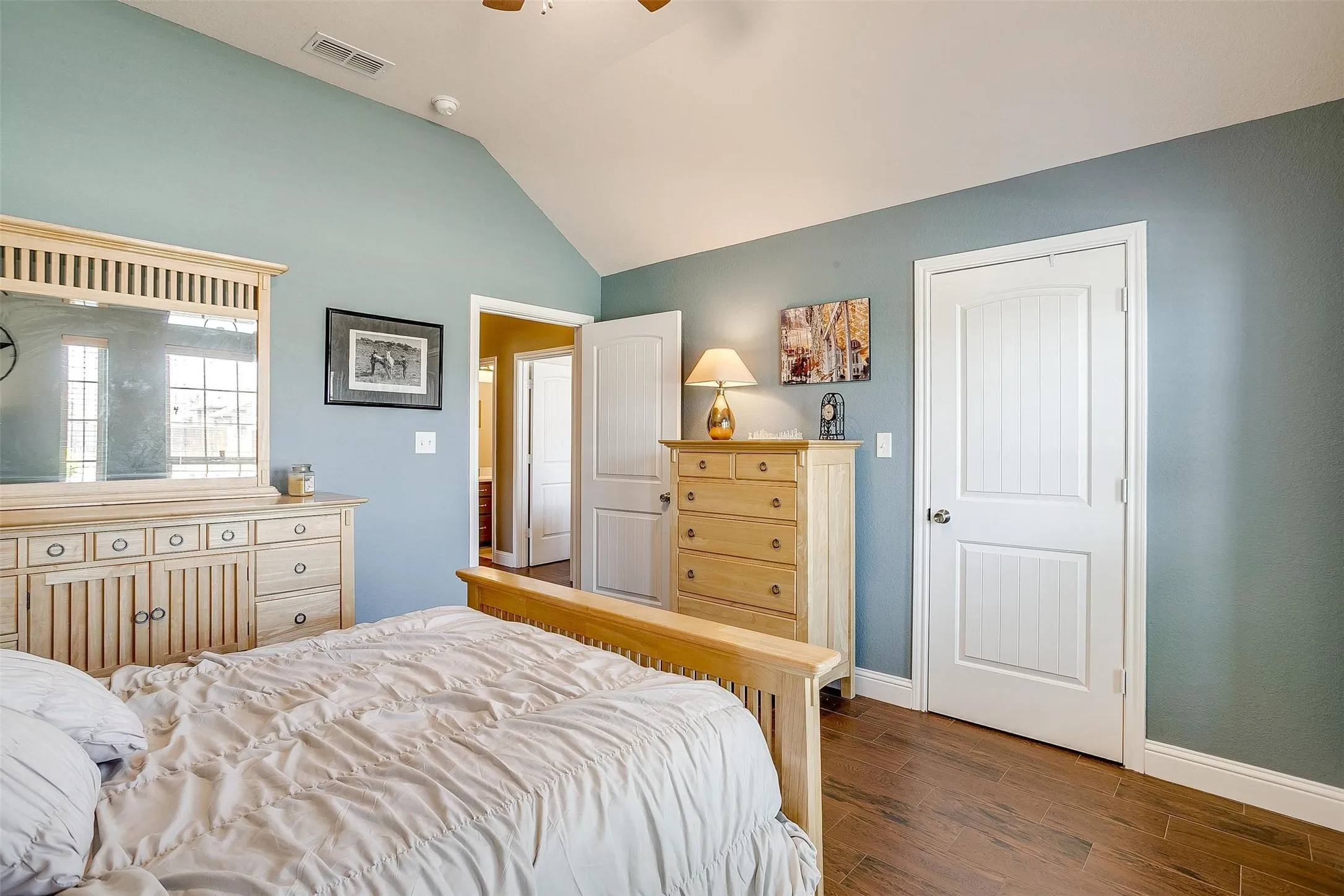 Vaulted ceiling, wood-finish flooring, white panel doors, and neutral wall tones