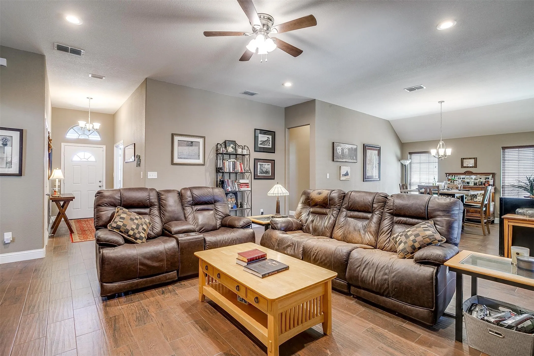 Wood-finish flooring throughout, vaulted ceiling, recessed lighting, ceiling fan, and a front entry door with an arched transom window