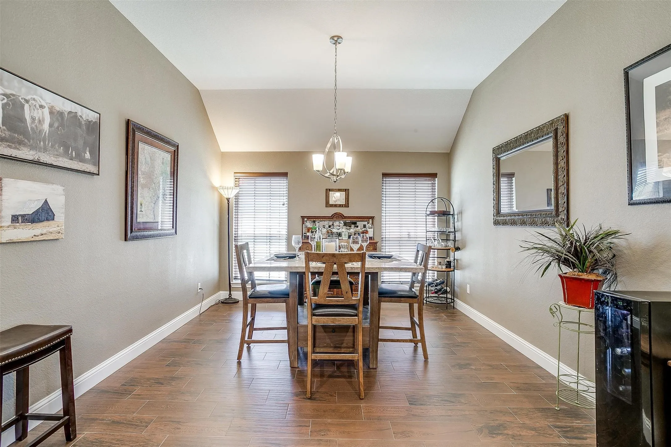 Vaulted ceiling, recessed lighting, wood-finish flooring, two large windows with blinds, and a chandelier