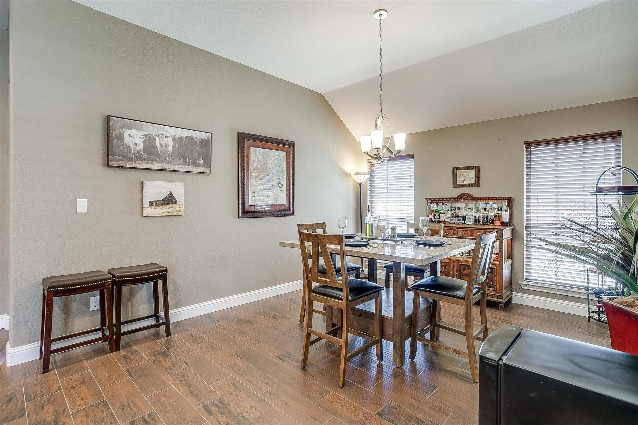Vaulted ceiling with an attached chandelier, wood-finish flooring, and white trim