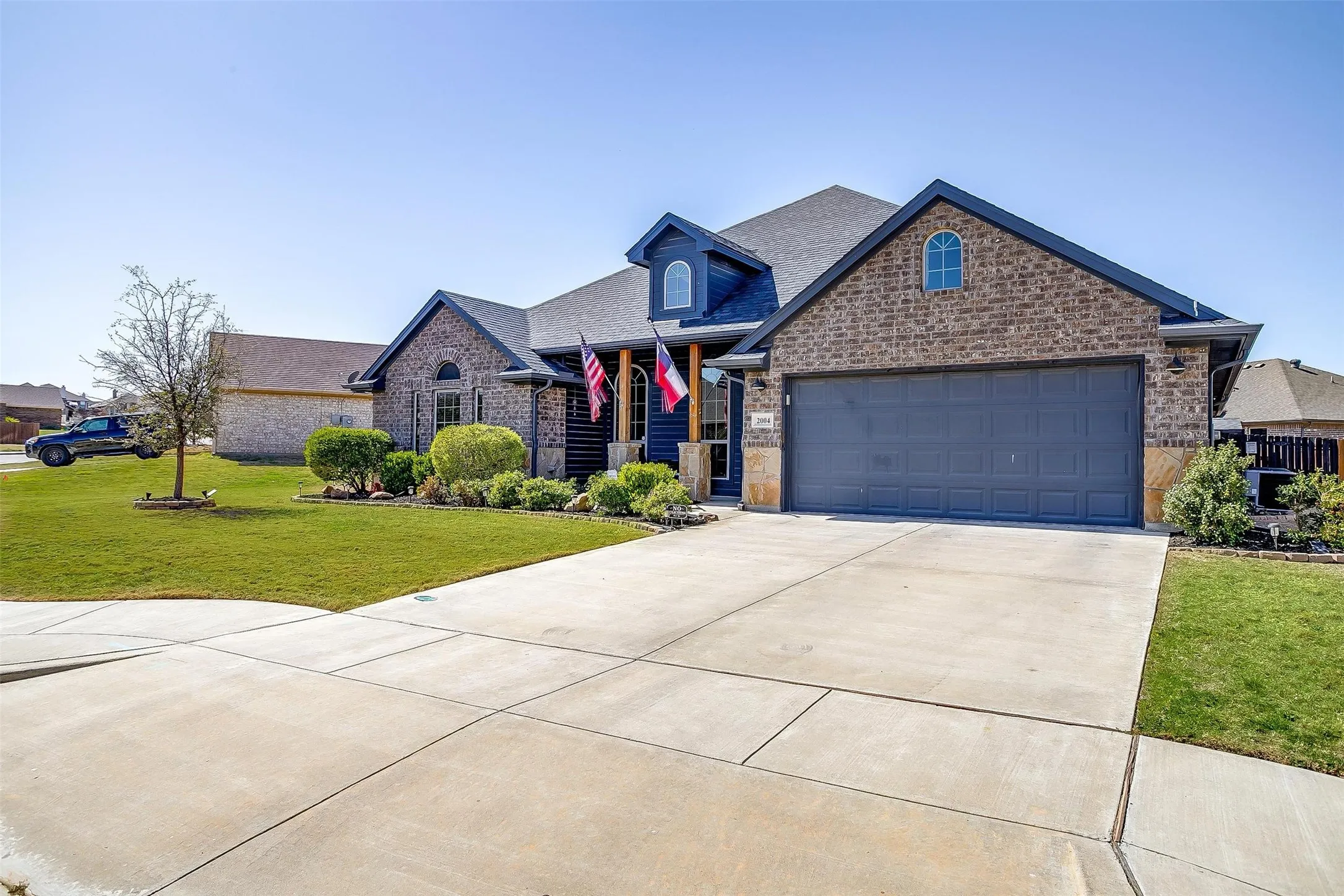 Brick and siding exterior with a concrete driveway, two-car garage, and landscaped front yard