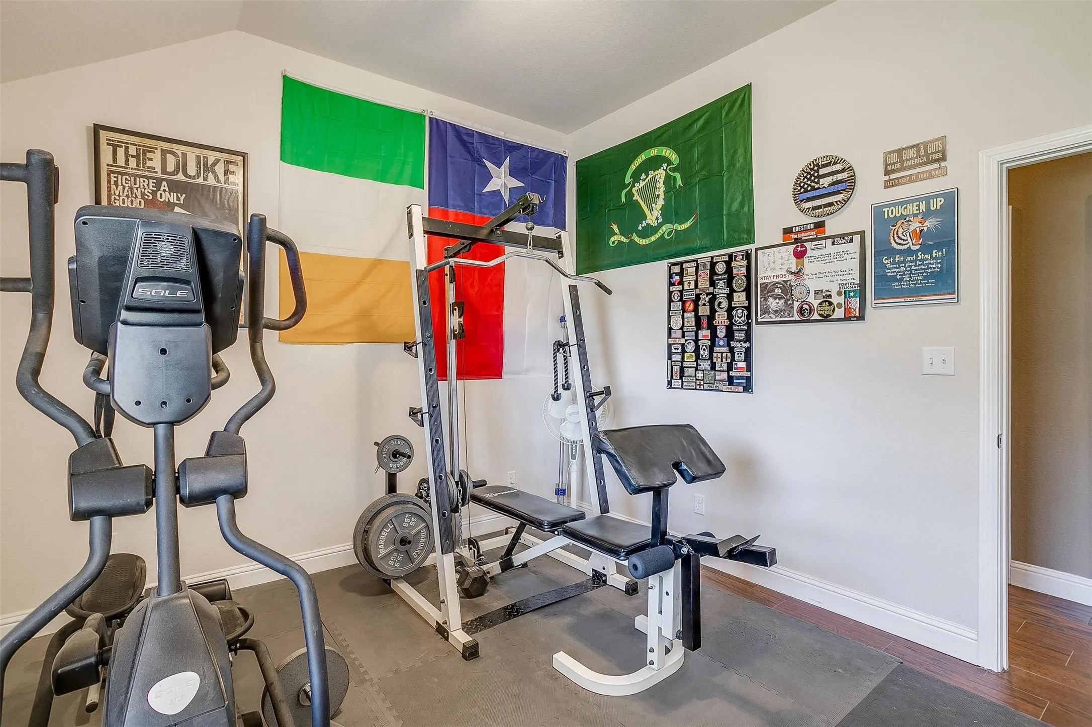 Versatile room with vaulted ceilings, neutral wall paint, and durable flooring