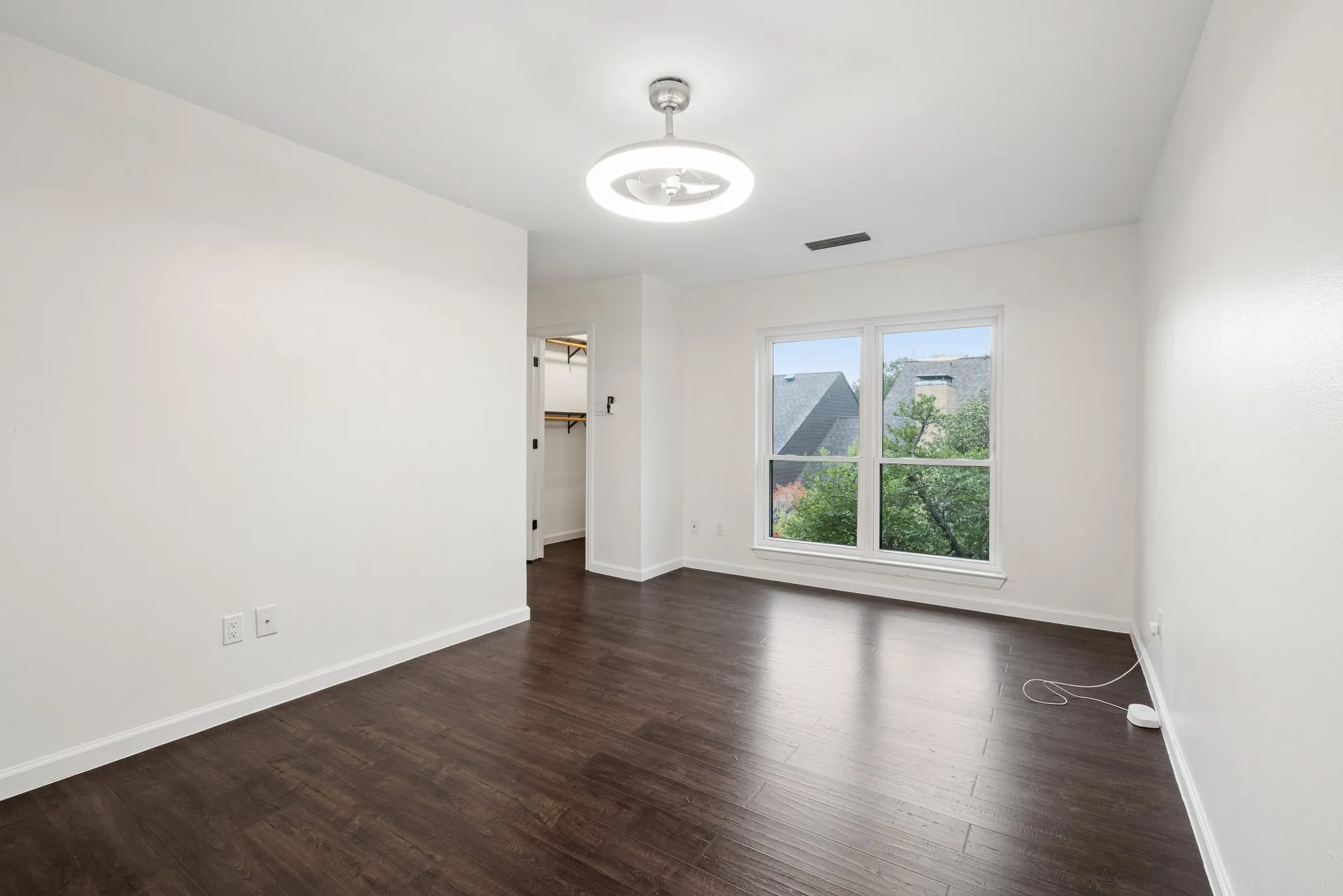 Bright corner room featuring dark wood-finish flooring, white walls, and large dual-pane windows with mountain backdrop