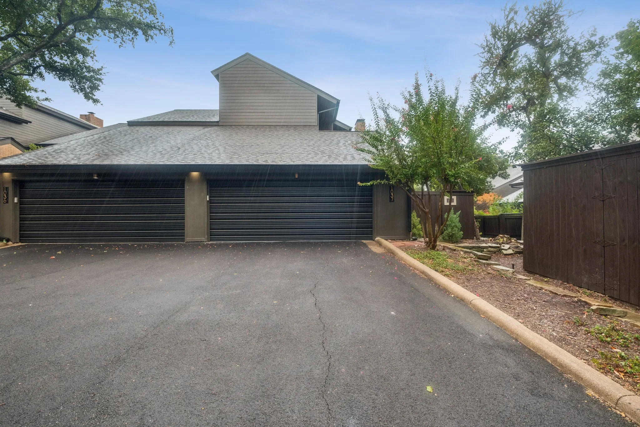 Two-car garage with black doors, exterior lighting, and a paved driveway