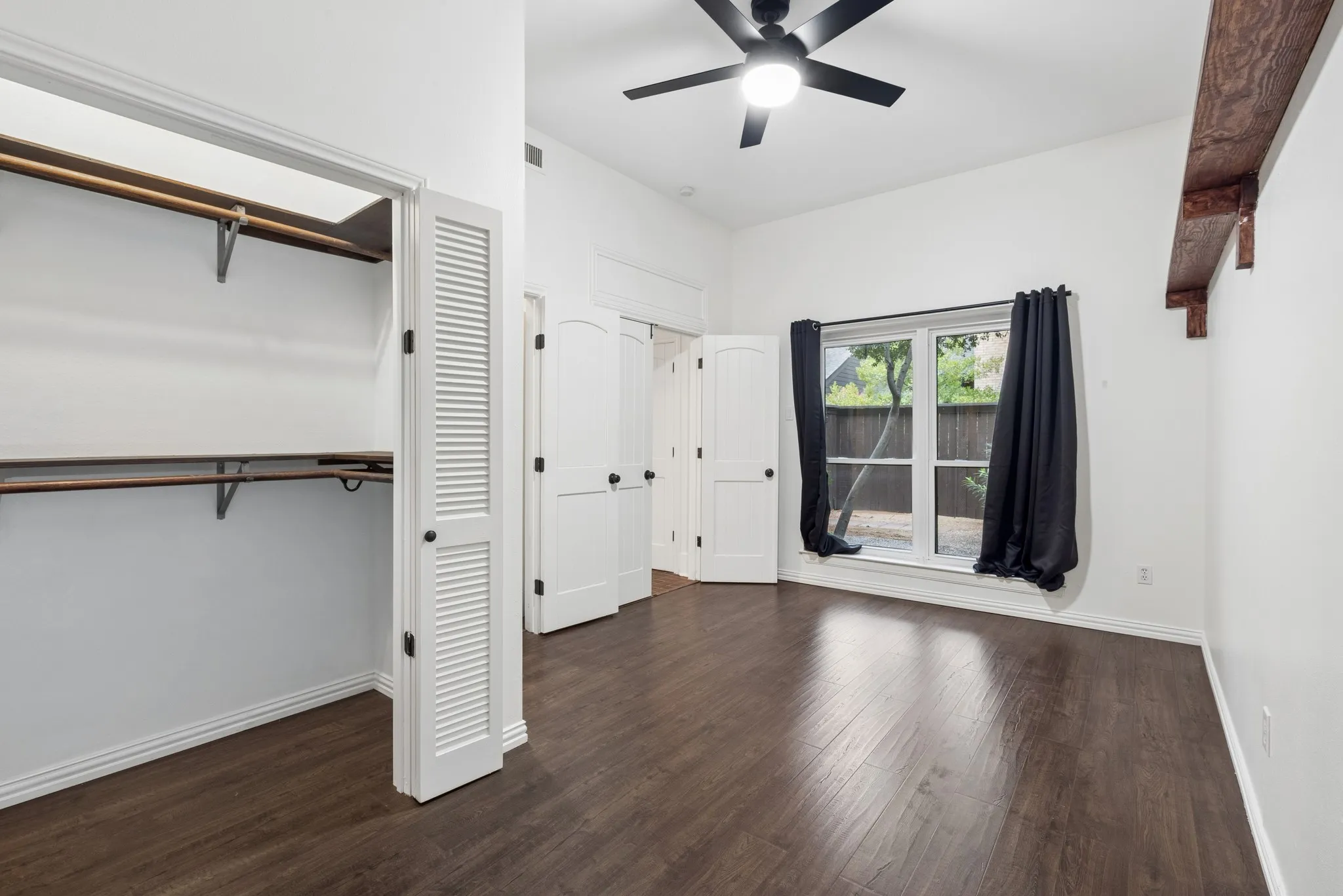 Vaulted ceilings, wood-finish flooring, a ceiling fan, louvered closet doors, and an arched interior door
