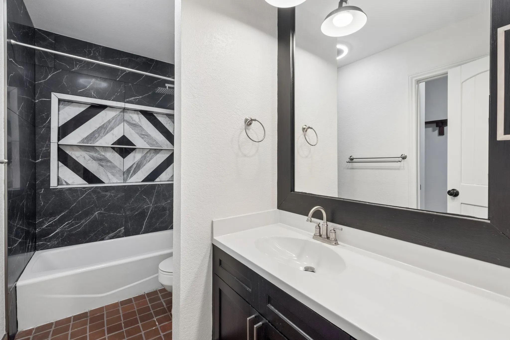 Bathroom featuring a dark wood-finish vanity with a single basin sink, a framed mirror, and a white countertop