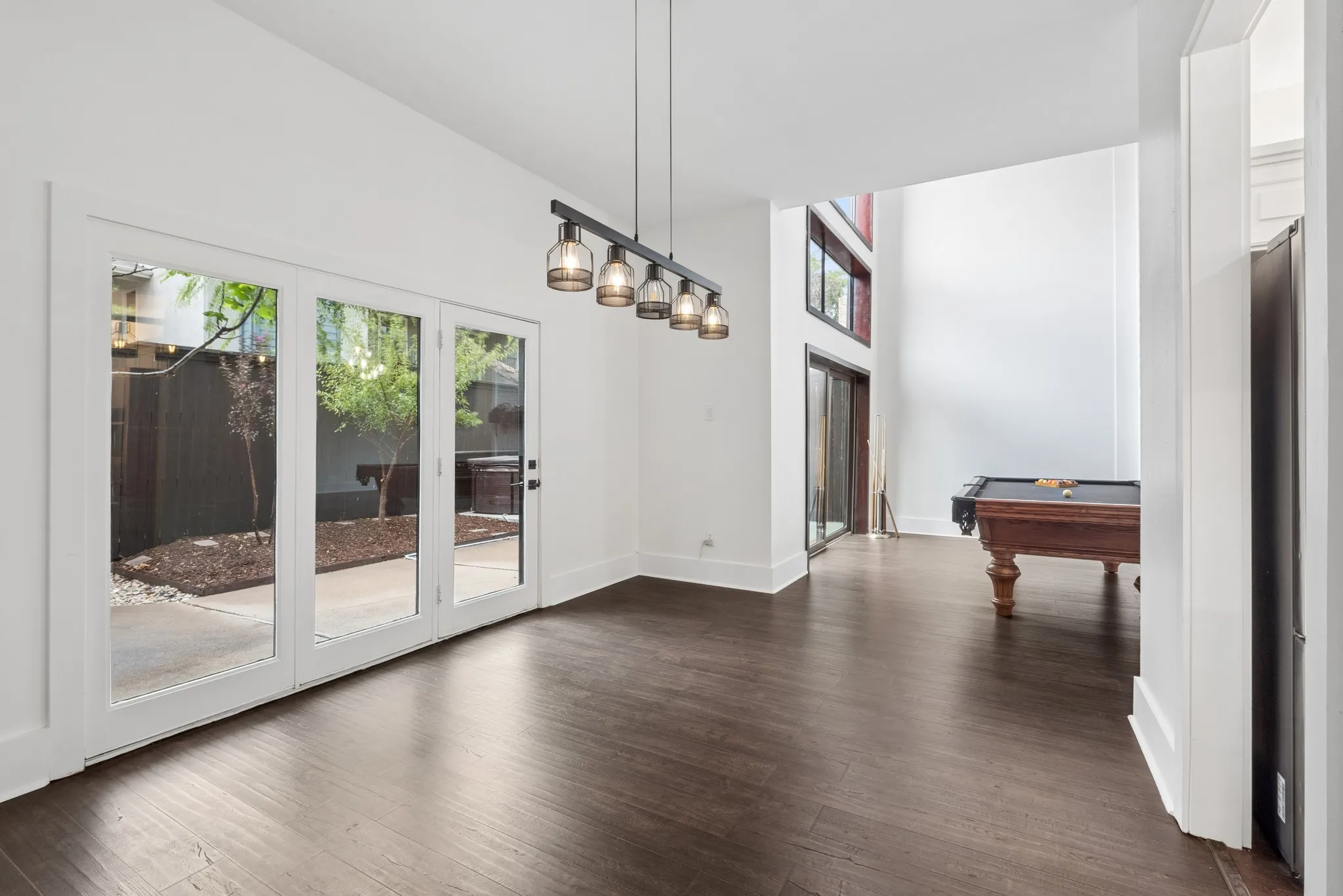 Hardwood-finish flooring, soaring vaulted ceilings, and a linear chandelier with glass shades