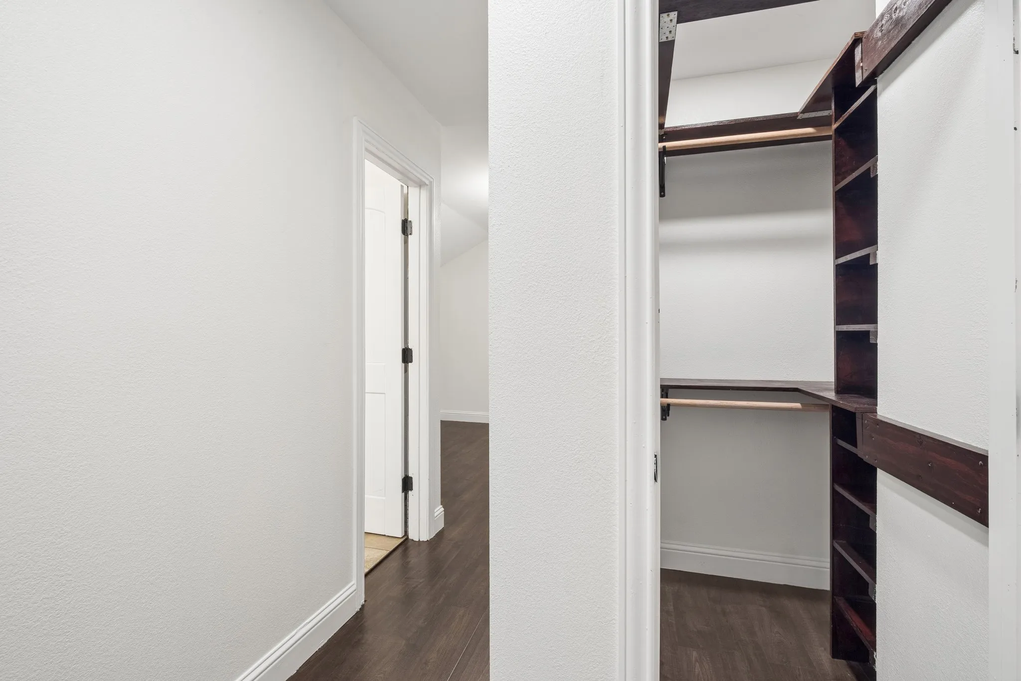 Custom closet system with wood-finish shelving and hanging rods