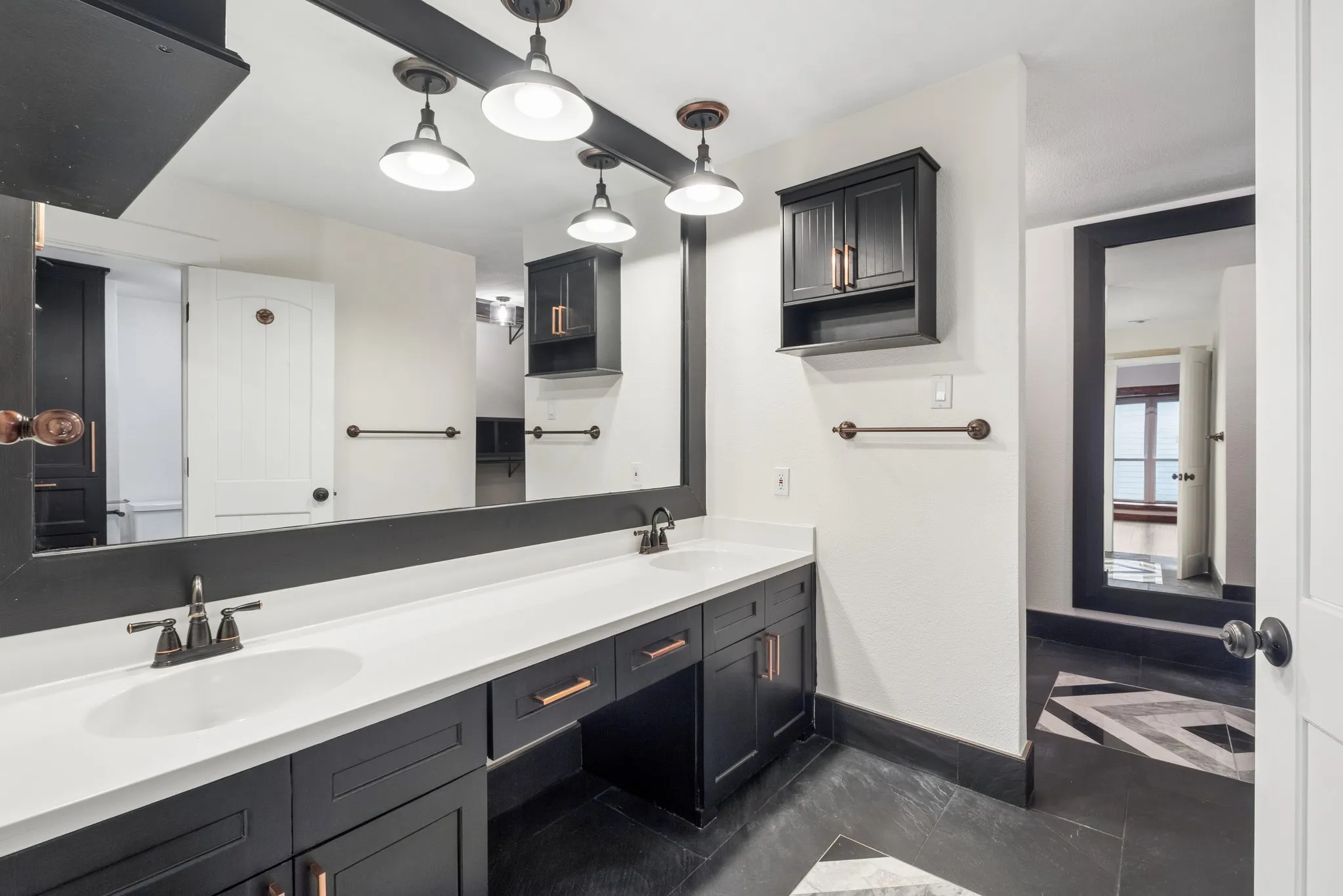 Dual vanity with white countertops, dark cabinetry, and bronze-finish hardware