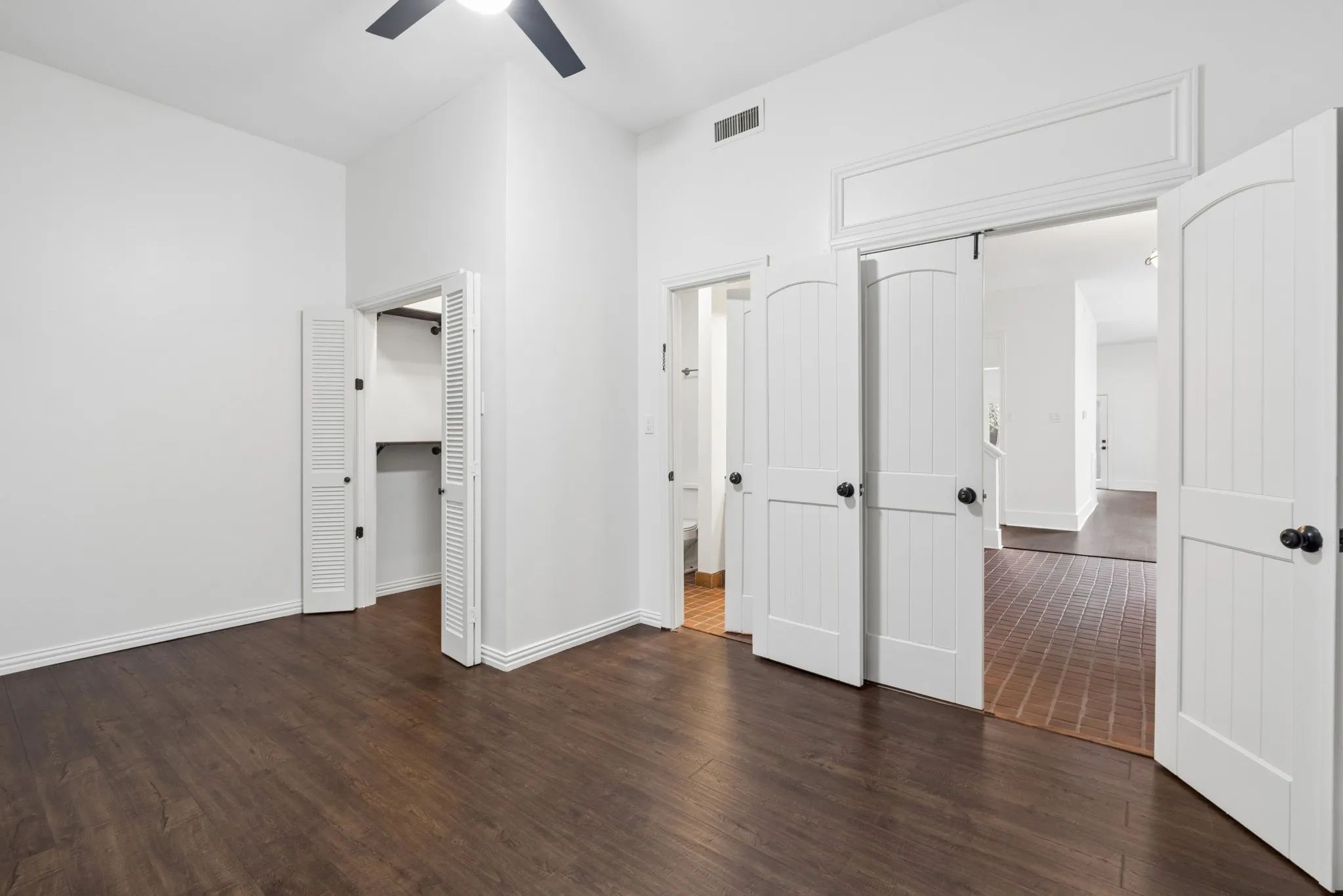 Wood-finish flooring, white walls, and a ceiling fan with integrated lighting