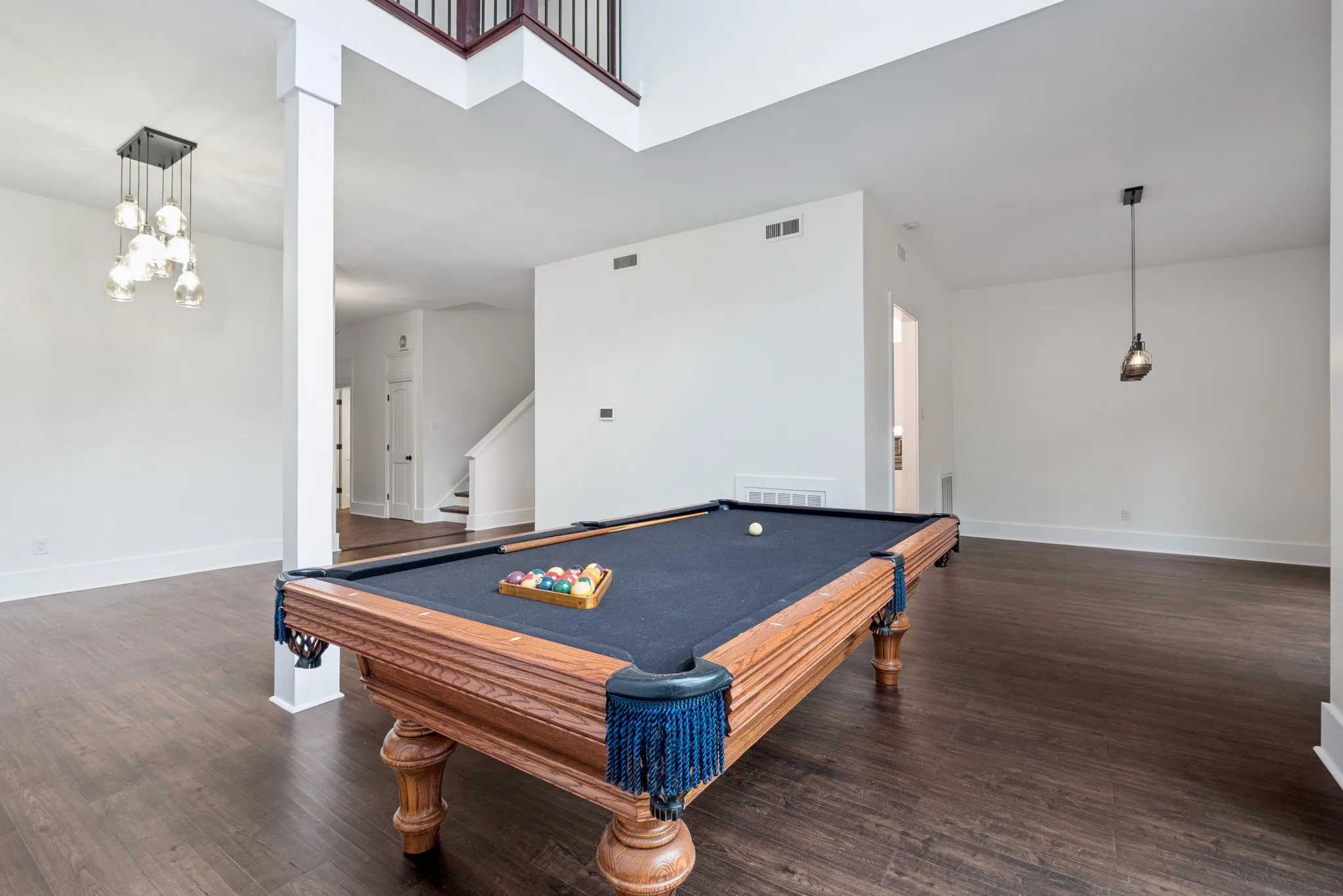 Expansive room featuring wood-finish flooring, high ceilings, and a modern multi-bulb pendant light fixture