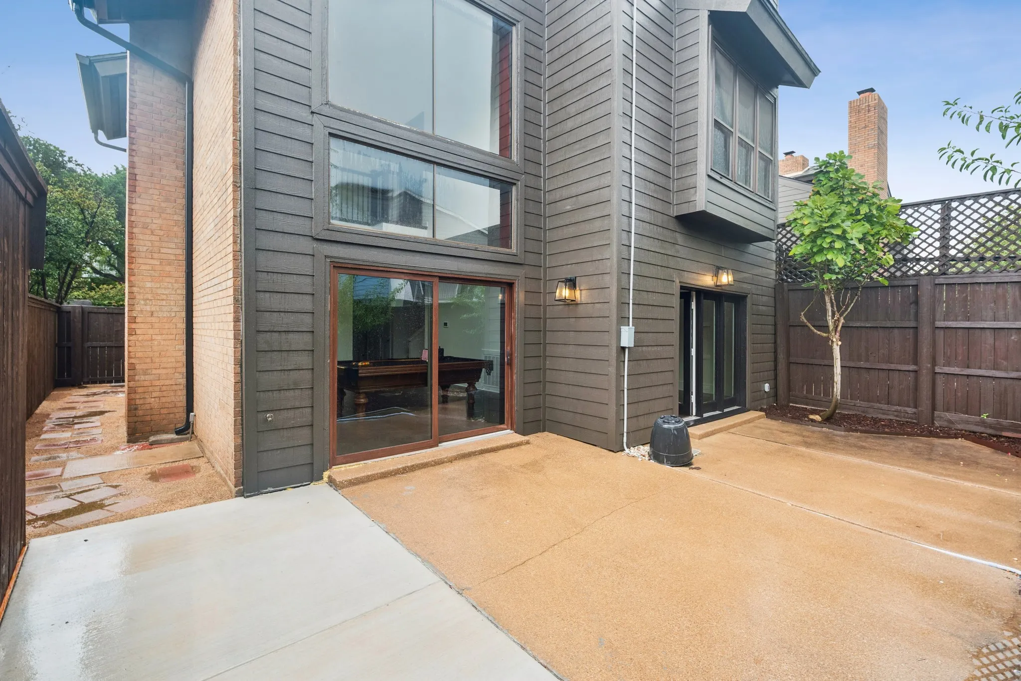 Siding exterior with multiple large windows, a sliding glass door, and exterior lighting fixtures