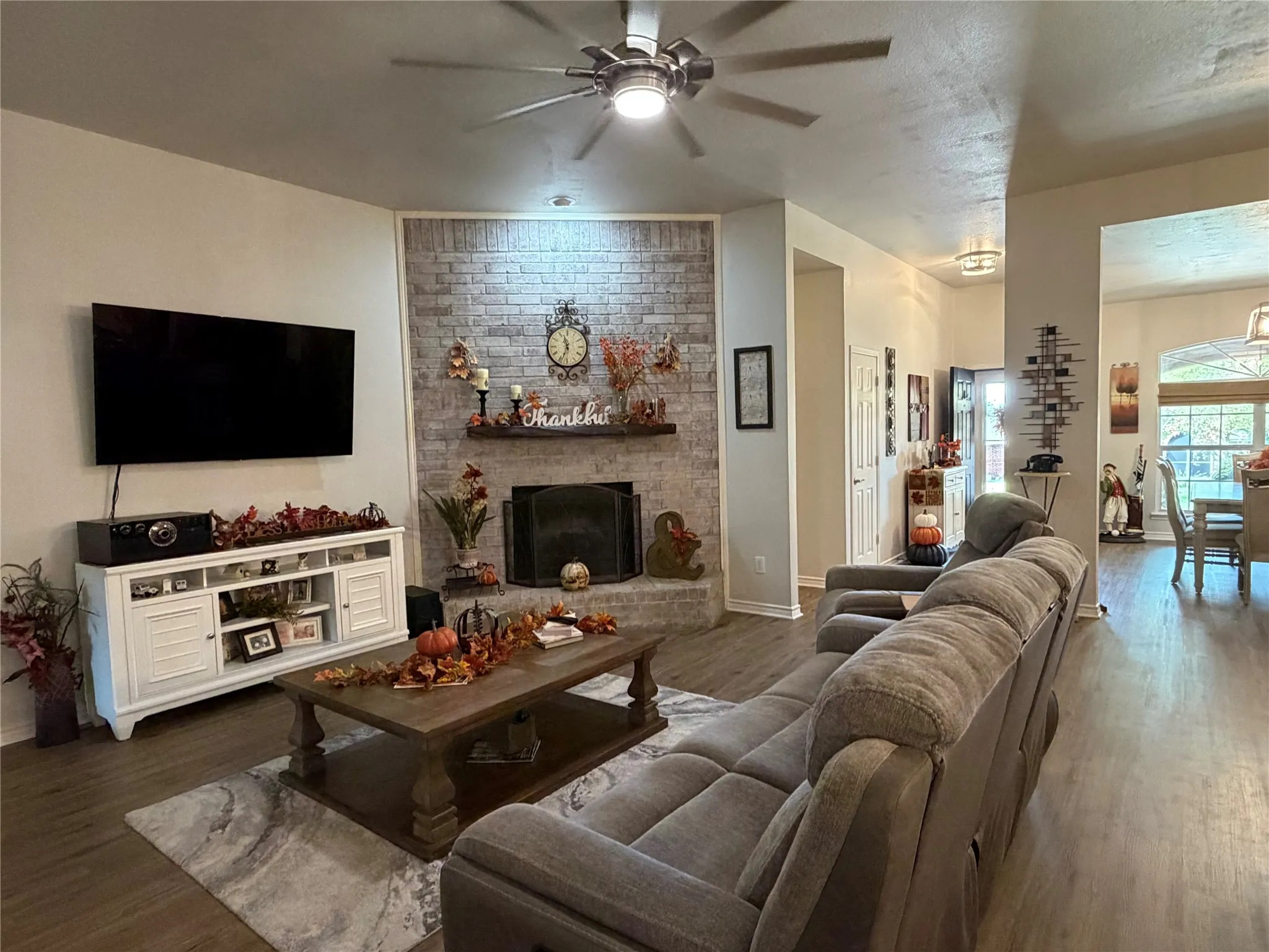 This Flows Seamlessly into a Warm and Welcoming Family Room, where a Cozy Brick Fireplace with a Wood Mantle Serves as the Perfect Centerpiece for Gatherings