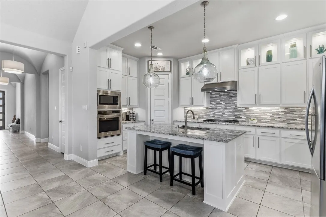 Kitchen Aid stainless steel appliances, five burner cooktop, microwave, convection oven, dishwasher, and trash/recycle drawer