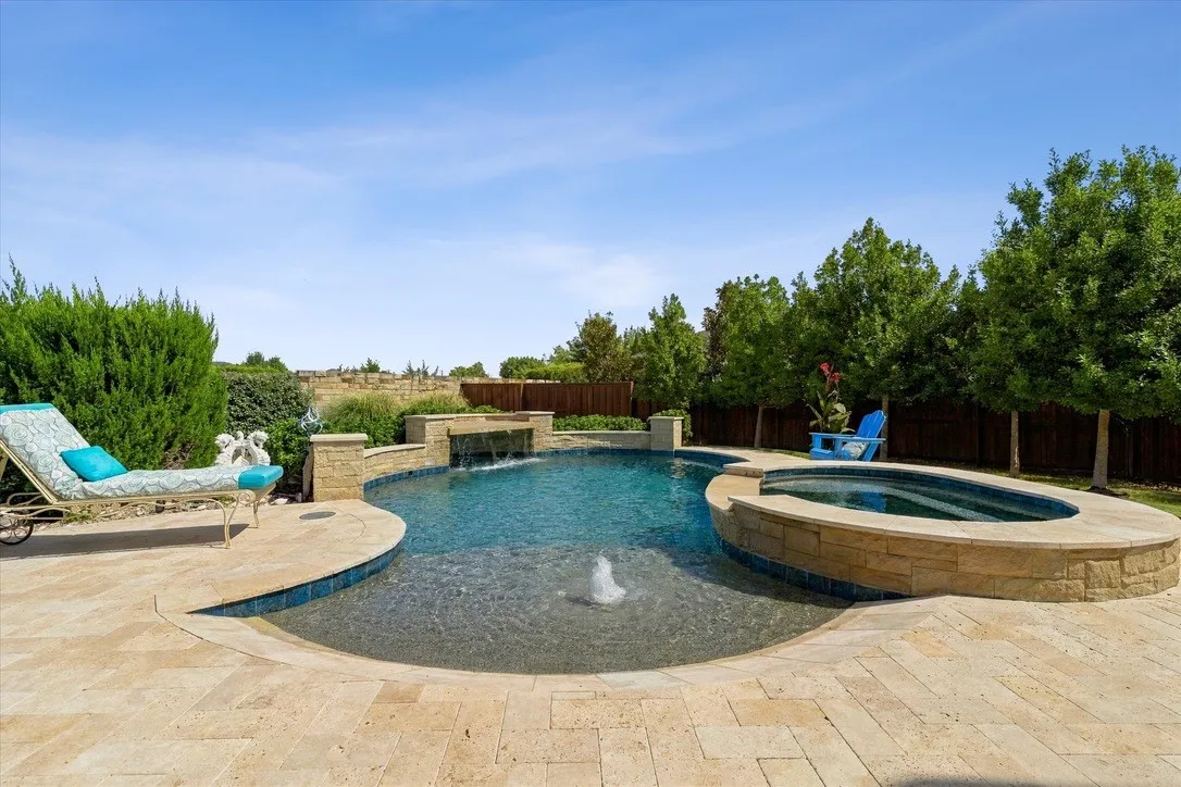 Zero-entry heated pool and spa, with waterfall, grotto, sun tanning ledge and beach area with umbrella holders.