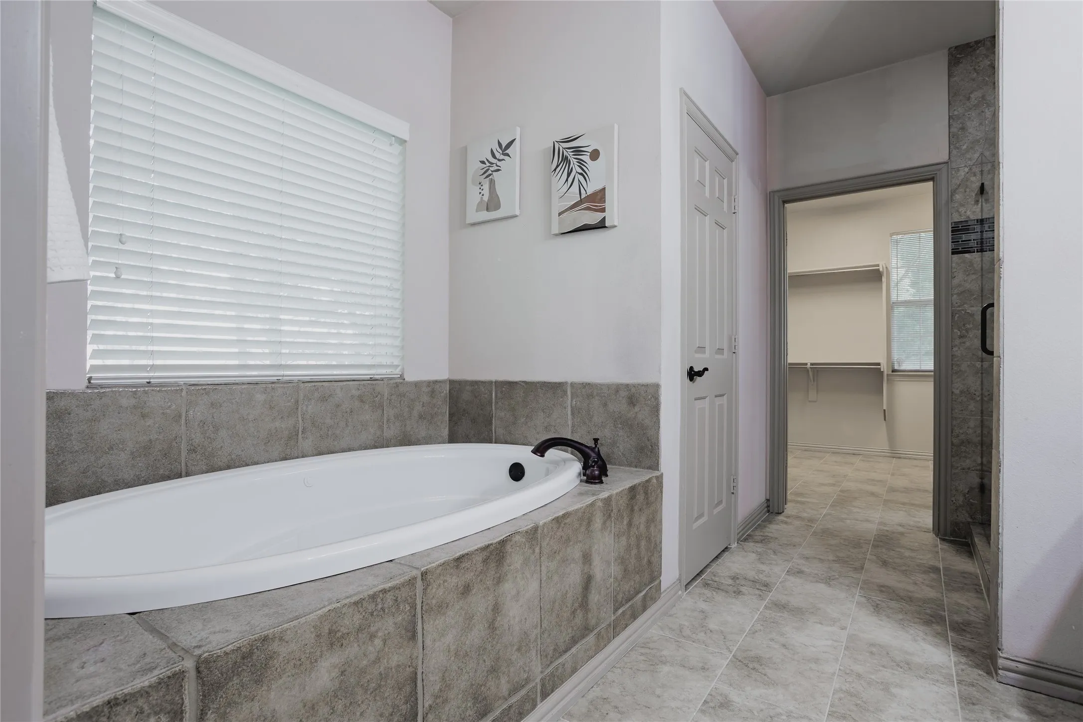 Deep soaking tub with a tiled surround, patterned floor tiling, and a separate glass-enclosed shower