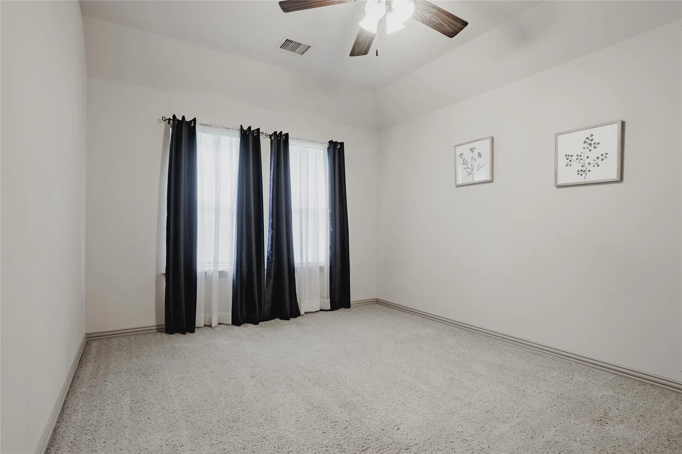Vaulted ceiling, ceiling fan with integrated lighting, wall-to-wall carpeting, and window treatments