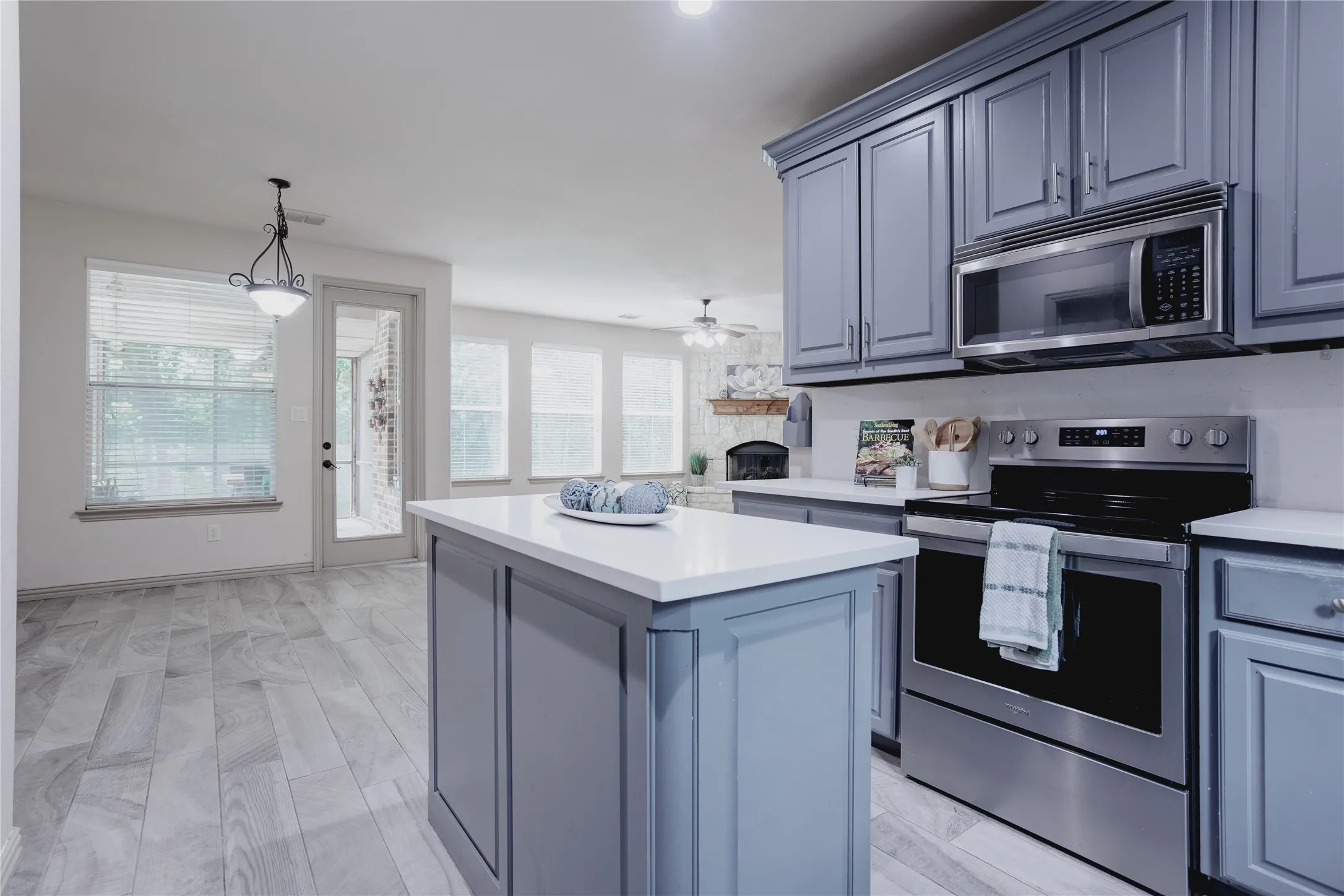 Kitchen featuring gray shaker-style cabinetry, stainless steel appliances, a center island with white countertop, and wood-finish flooring