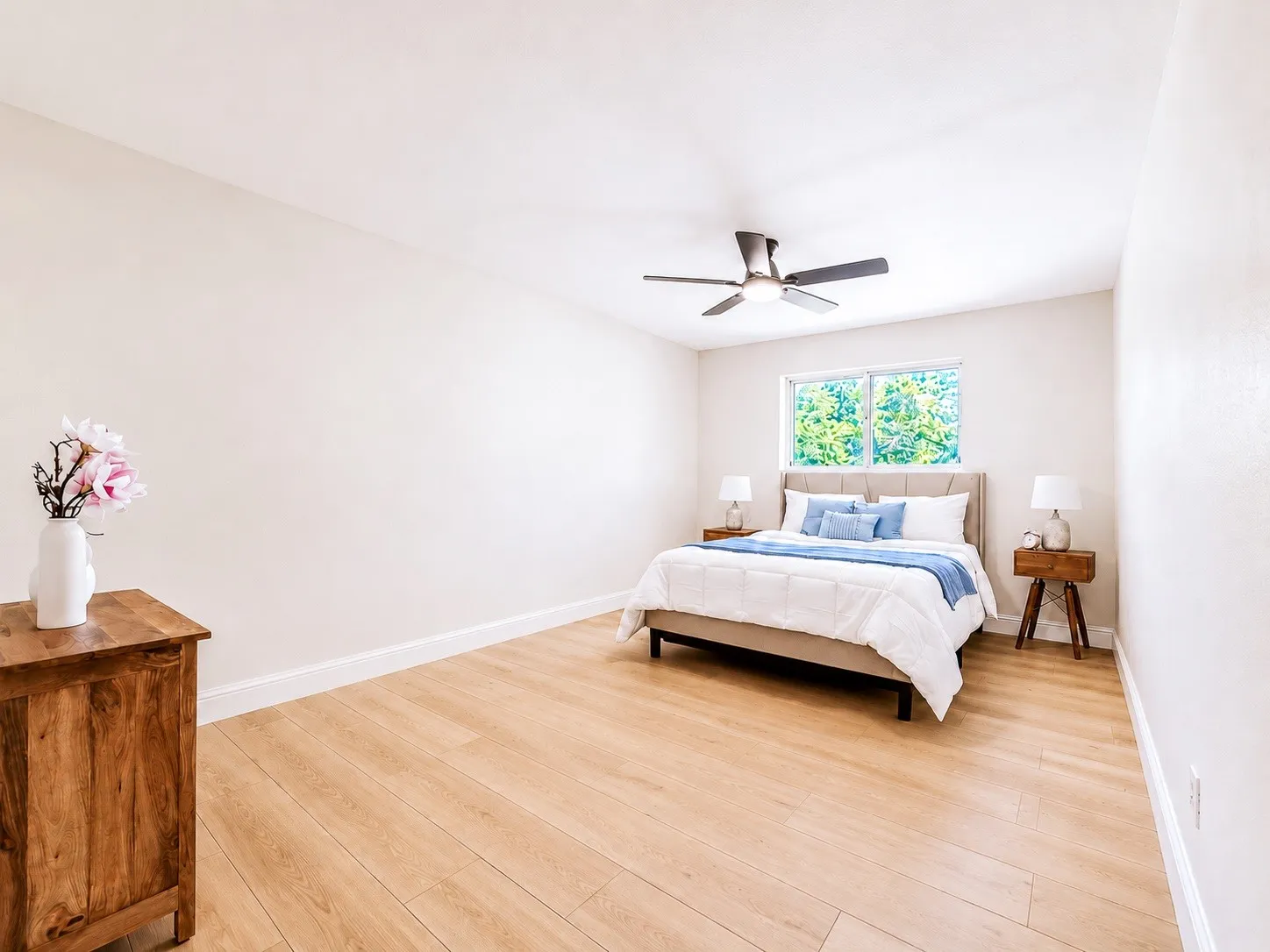 Light wood-finish flooring with white trim, a ceiling fan, and a double window