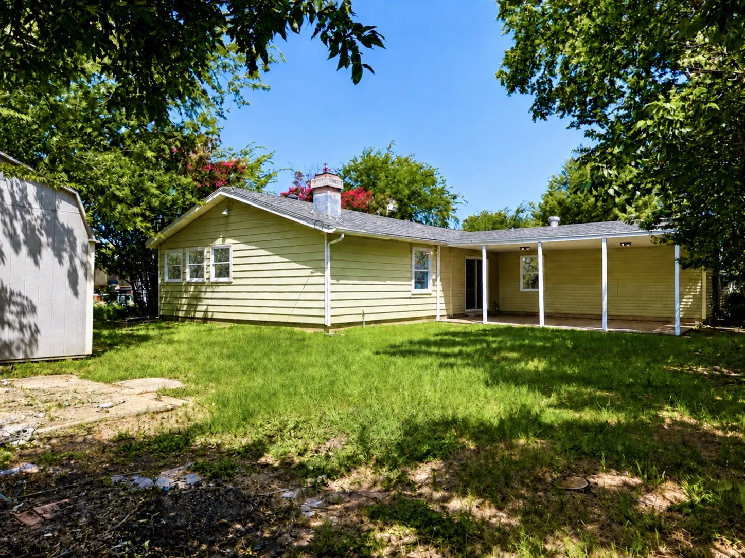 Expansive backyard featuring a covered patio, a detached shed, and a chimney
