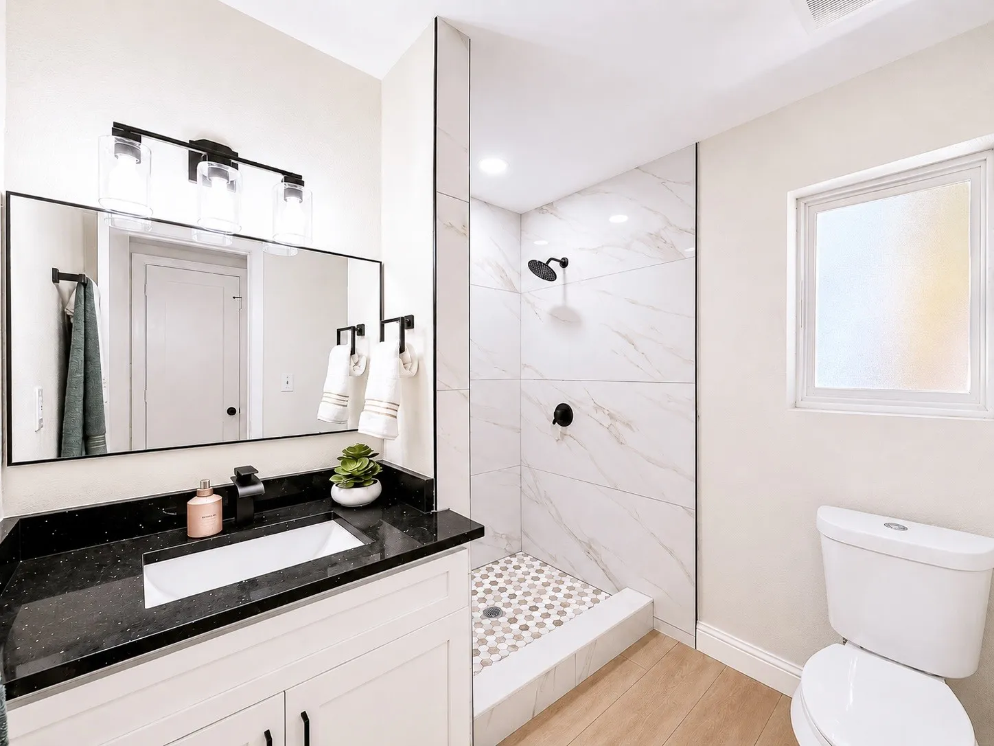 White vanity with black countertop, rectangular undermount sink, and black faucet