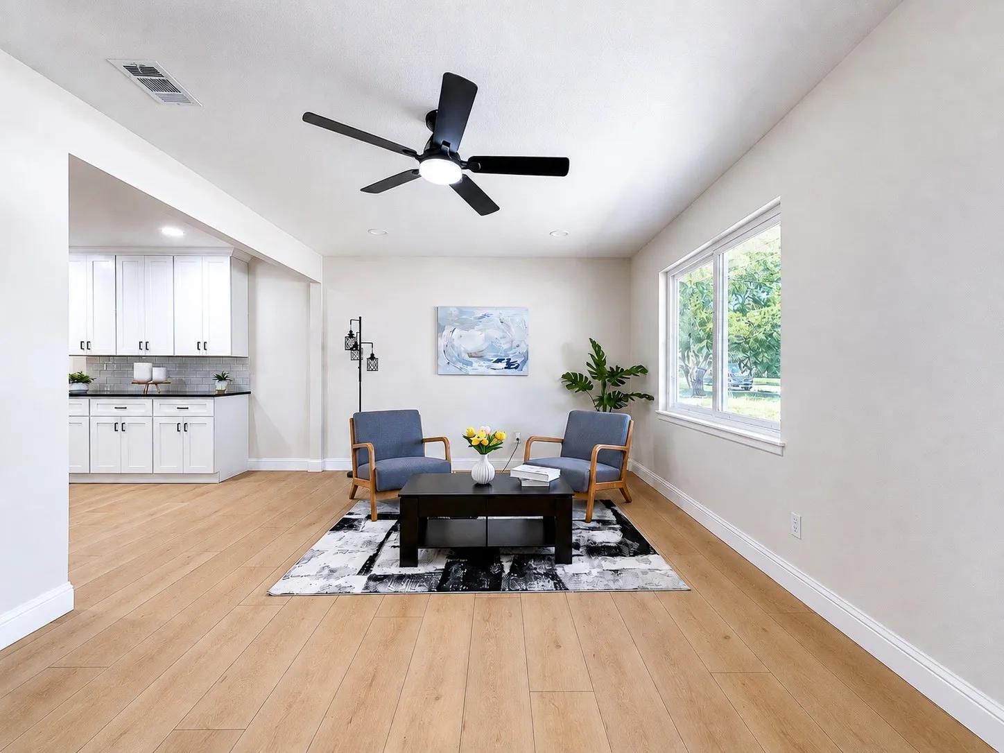 Open-concept living area featuring wood-finish flooring, a contemporary ceiling fan, and a large window