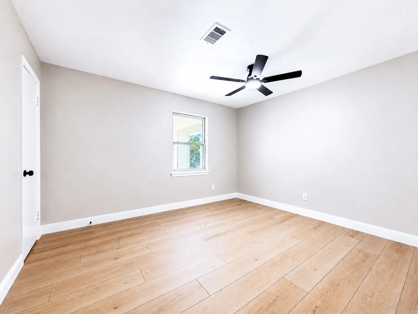 Wood-finish flooring, neutral wall tones, modern ceiling fan, and a double-pane window