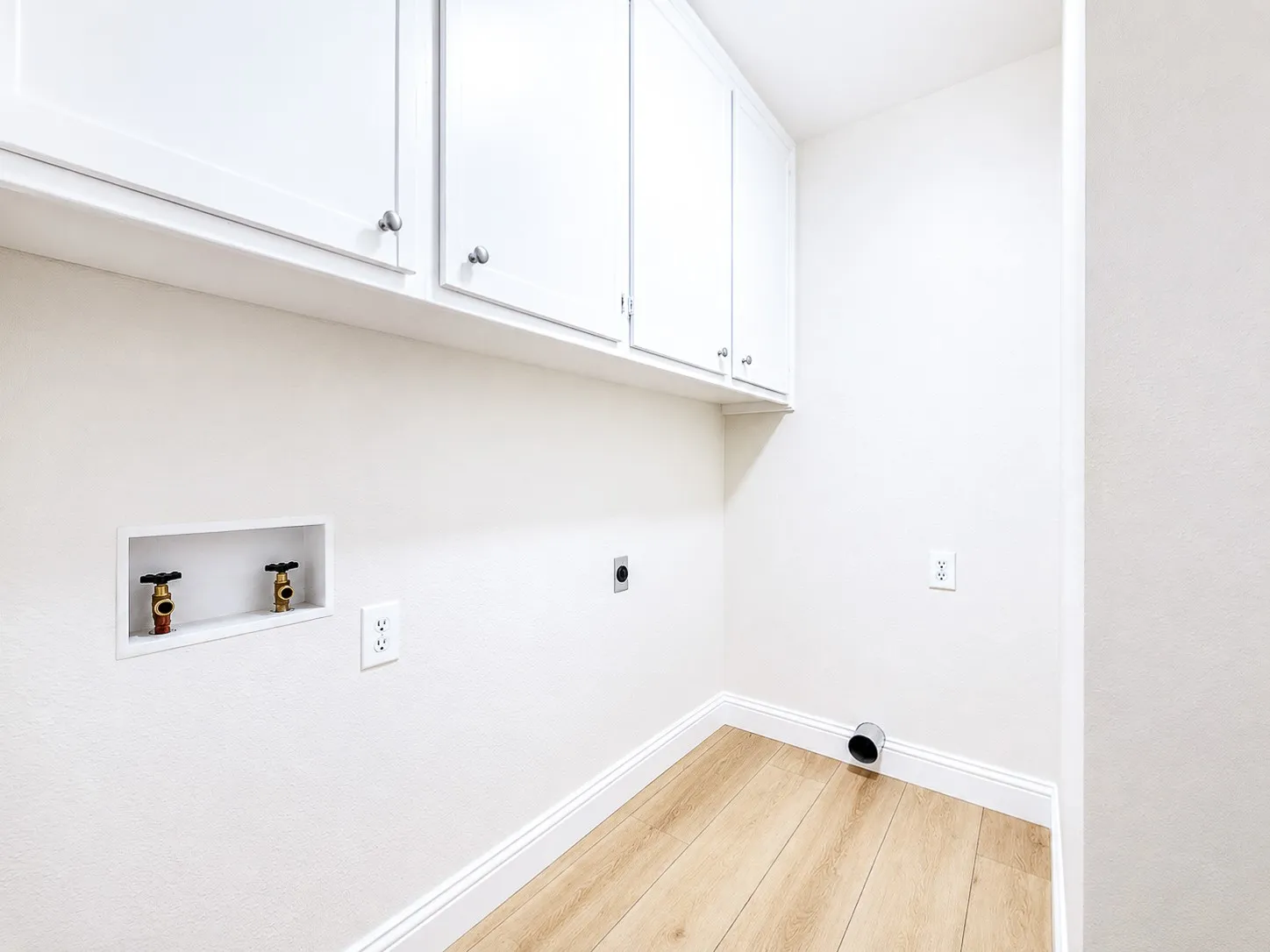 White shaker-style cabinetry with chrome pulls, wood-finish flooring, and crisp white walls