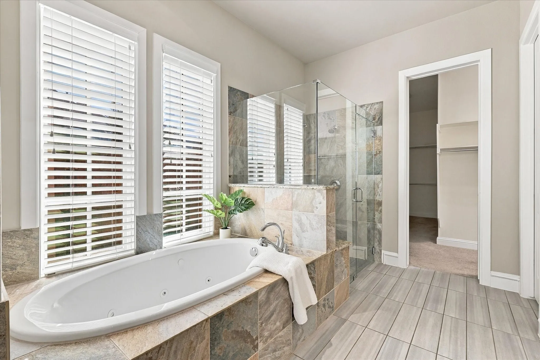 Spa-like primary bathroom with jetted tub and walk-in shower with frameless glass
