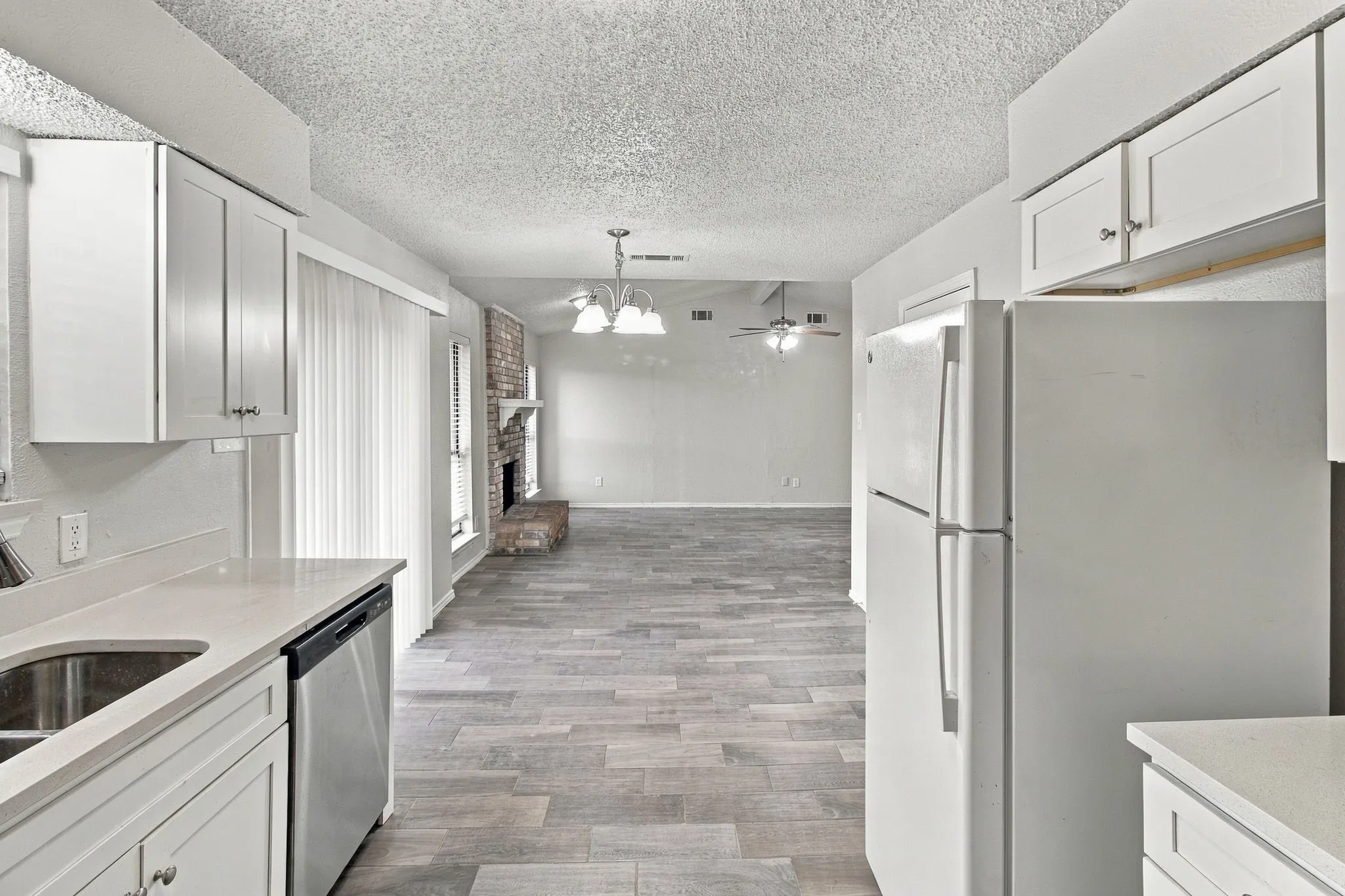 White cabinetry with chrome hardware, light-toned countertops, stainless steel dishwasher, and wood-finish flooring