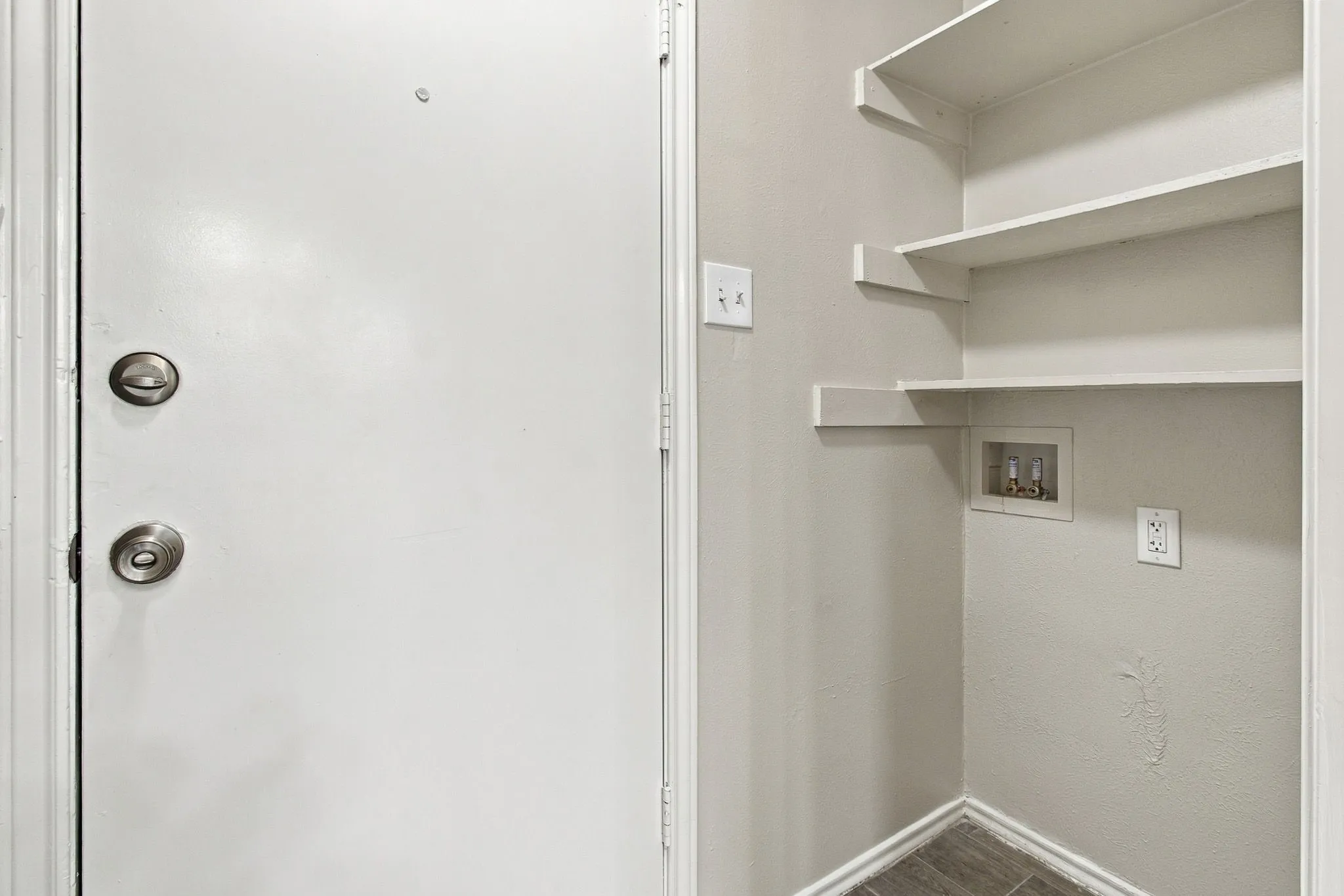 Laundry area with built-in shelving and wood-finish flooring