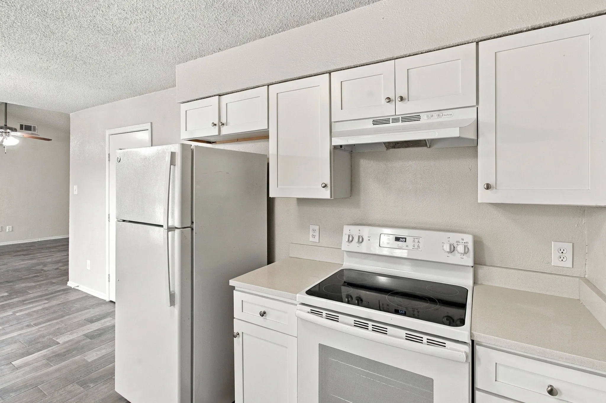 Kitchen featuring white cabinetry, light-toned countertops, a white electric range, and a white refrigerator