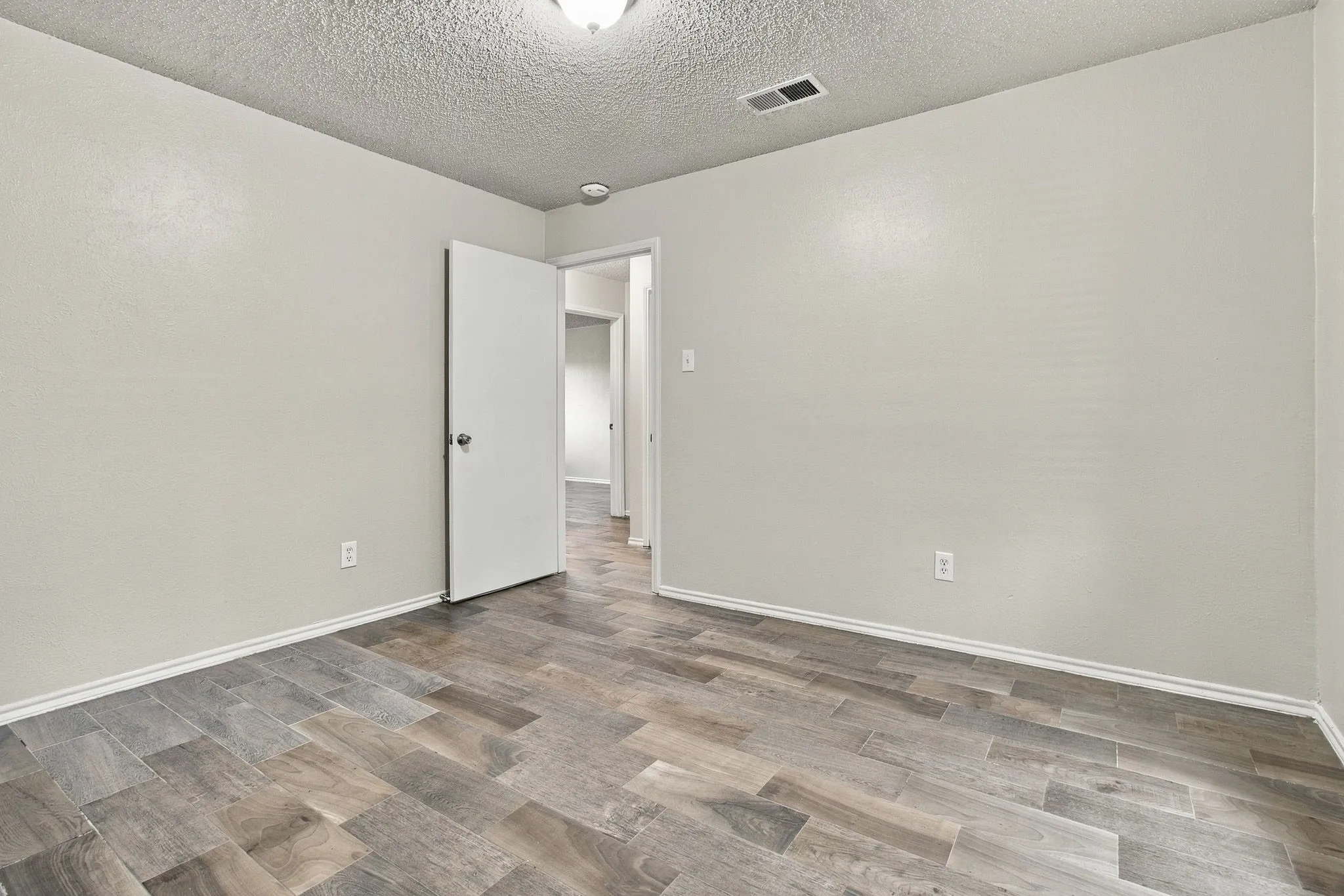 Recessed lighting, light gray wall color, textured ceiling, and wood-finish flooring