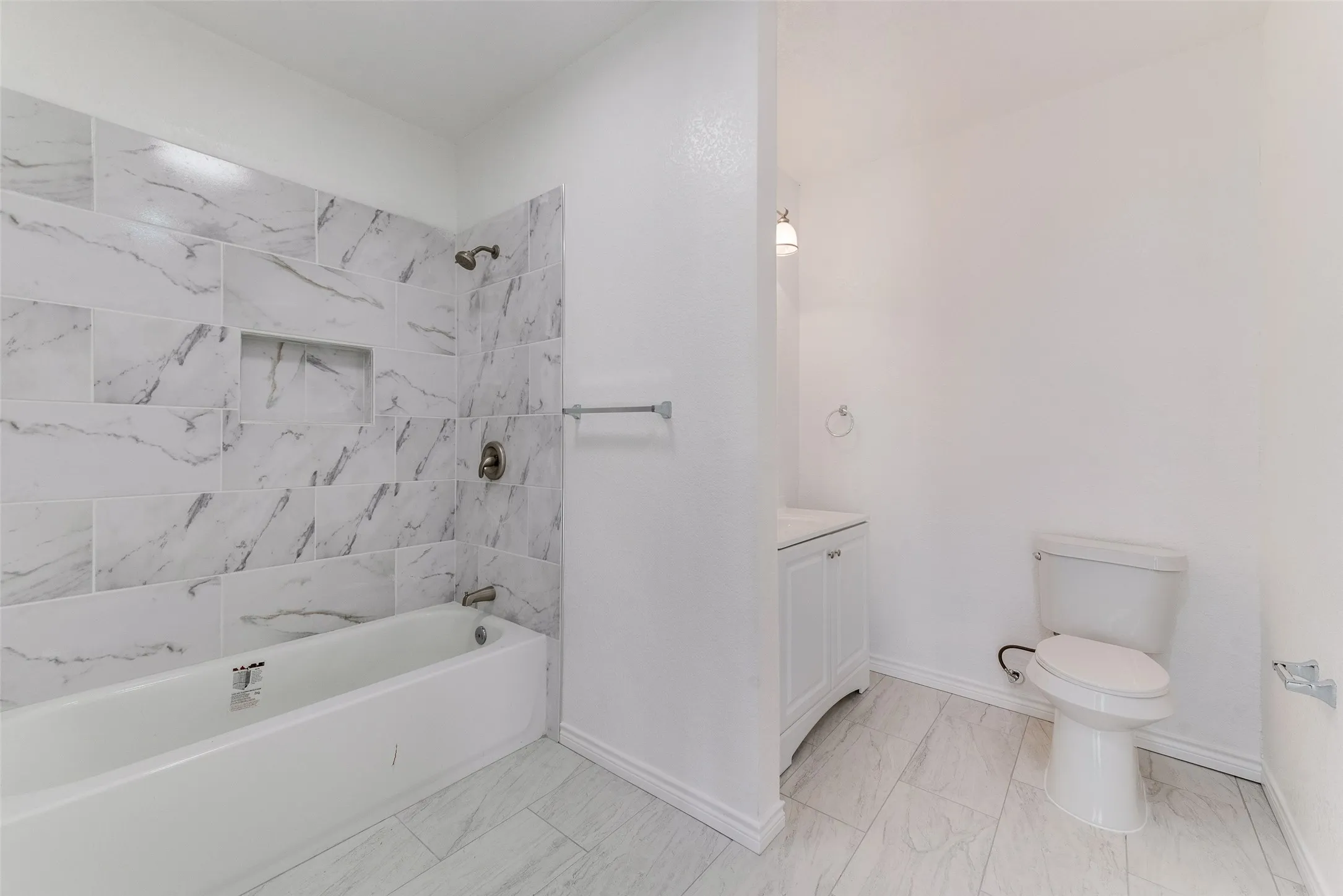 Tiled shower with an integrated niche, white tub, modern vanity with a rectangular sink, and tile flooring