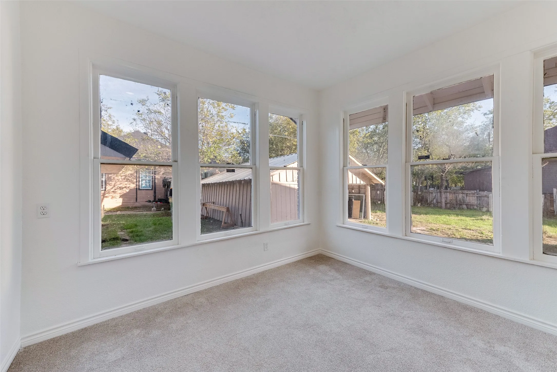 Light-colored wall-to-wall carpeting, white walls, multiple windows, and white trim
