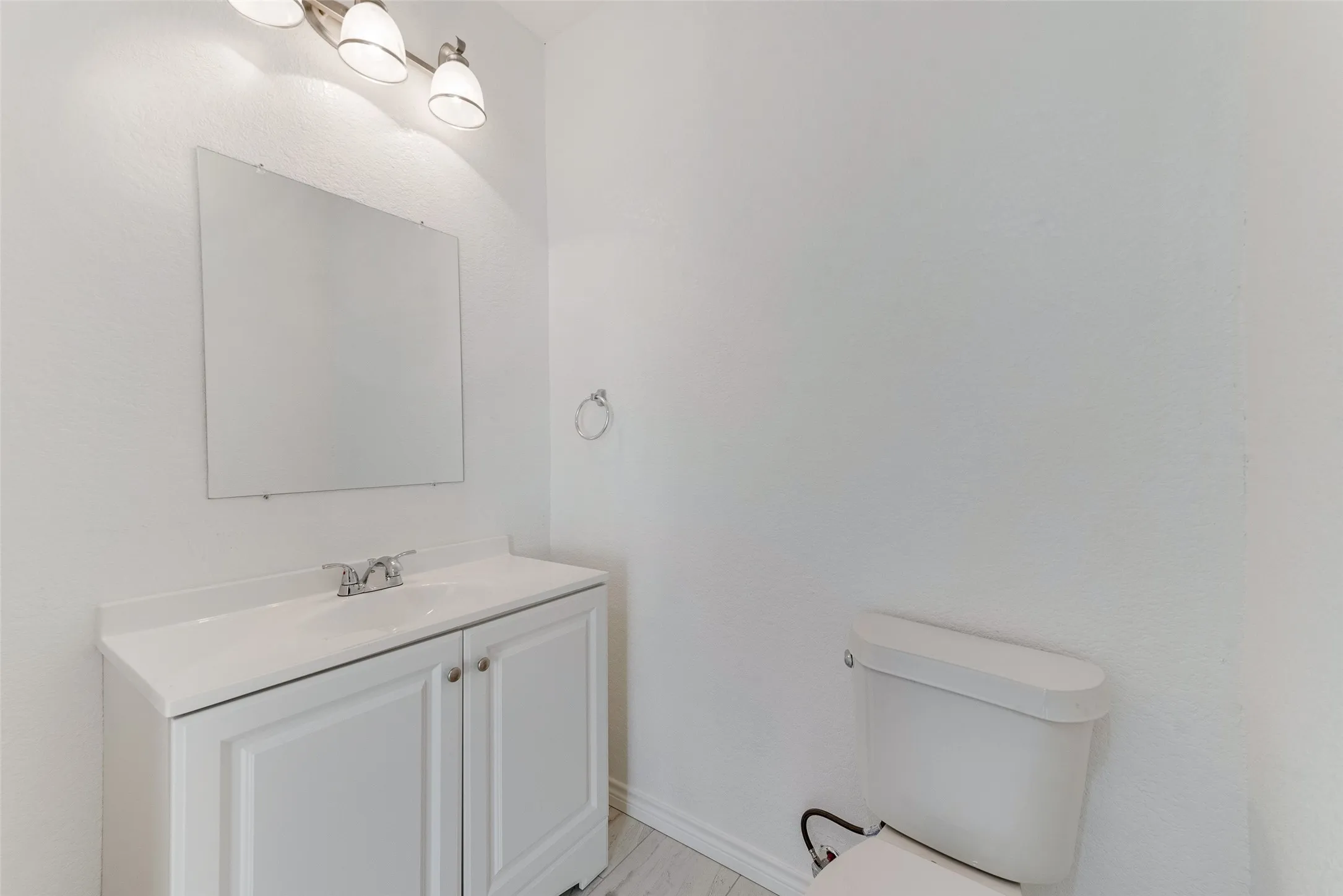 White vanity with integrated sink, chrome faucet, and a wall-mounted mirror
