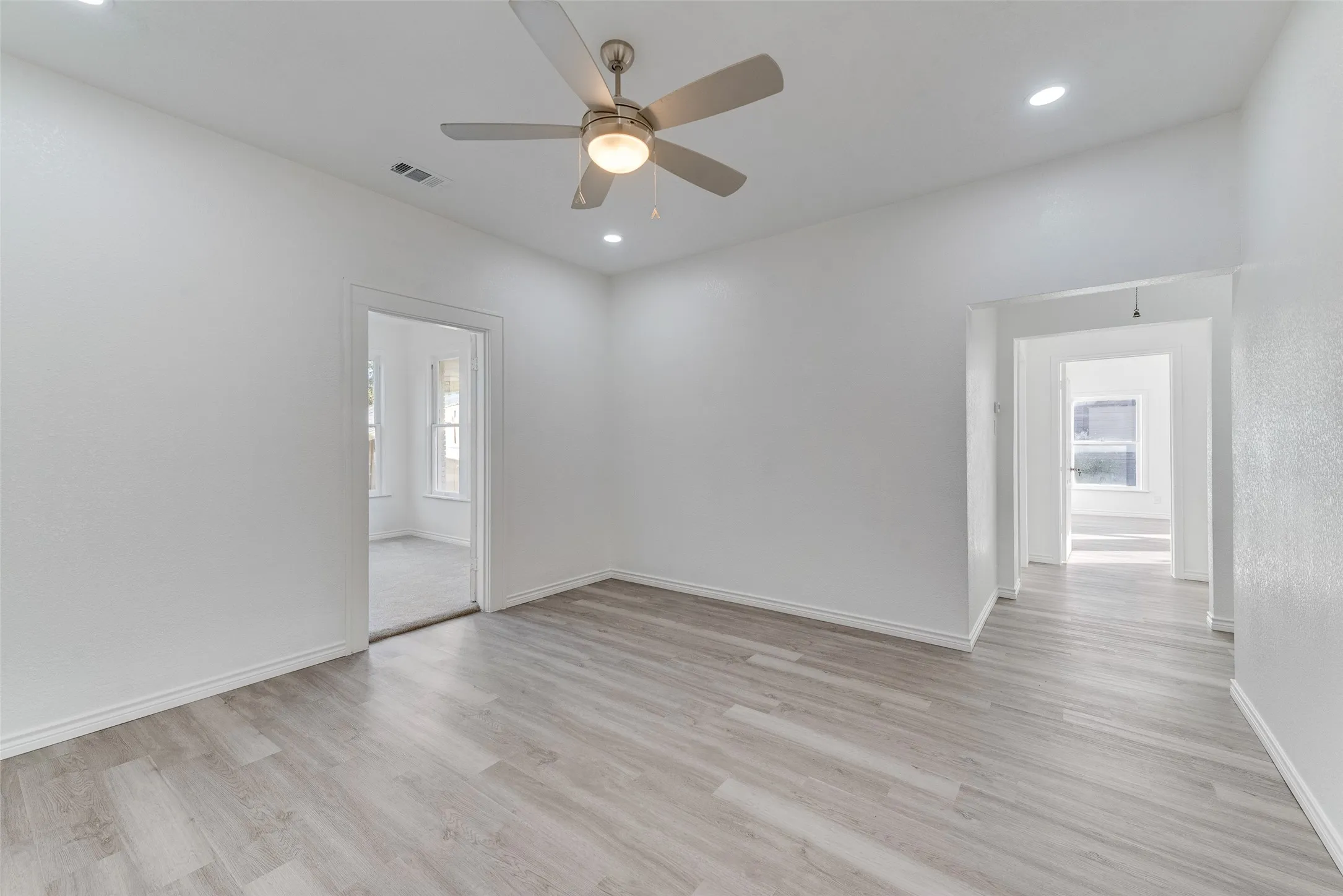 Spacious room featuring wood-finish flooring, recessed lighting, and a ceiling fan