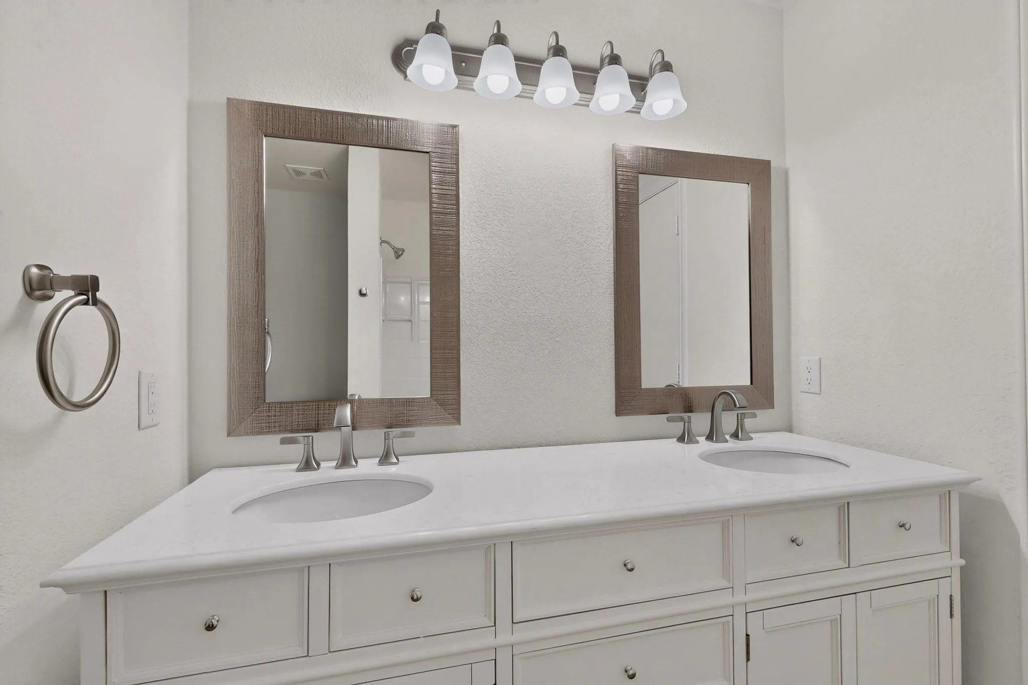 Dual vanity with white cabinetry and integrated sinks, brushed nickel fixtures, and individual framed mirrors