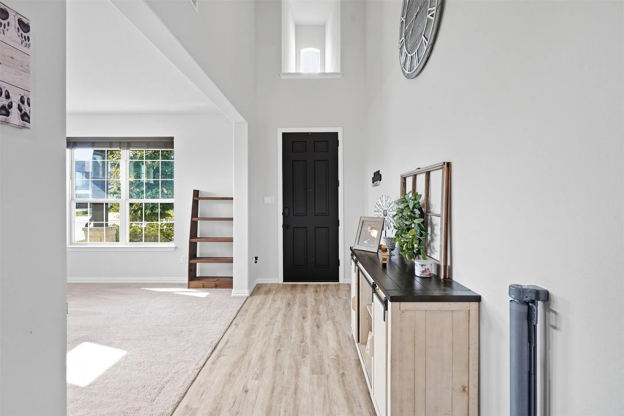 Entryway featuring a black paneled door, wood-finish flooring, and high ceilings with an upper transom window
