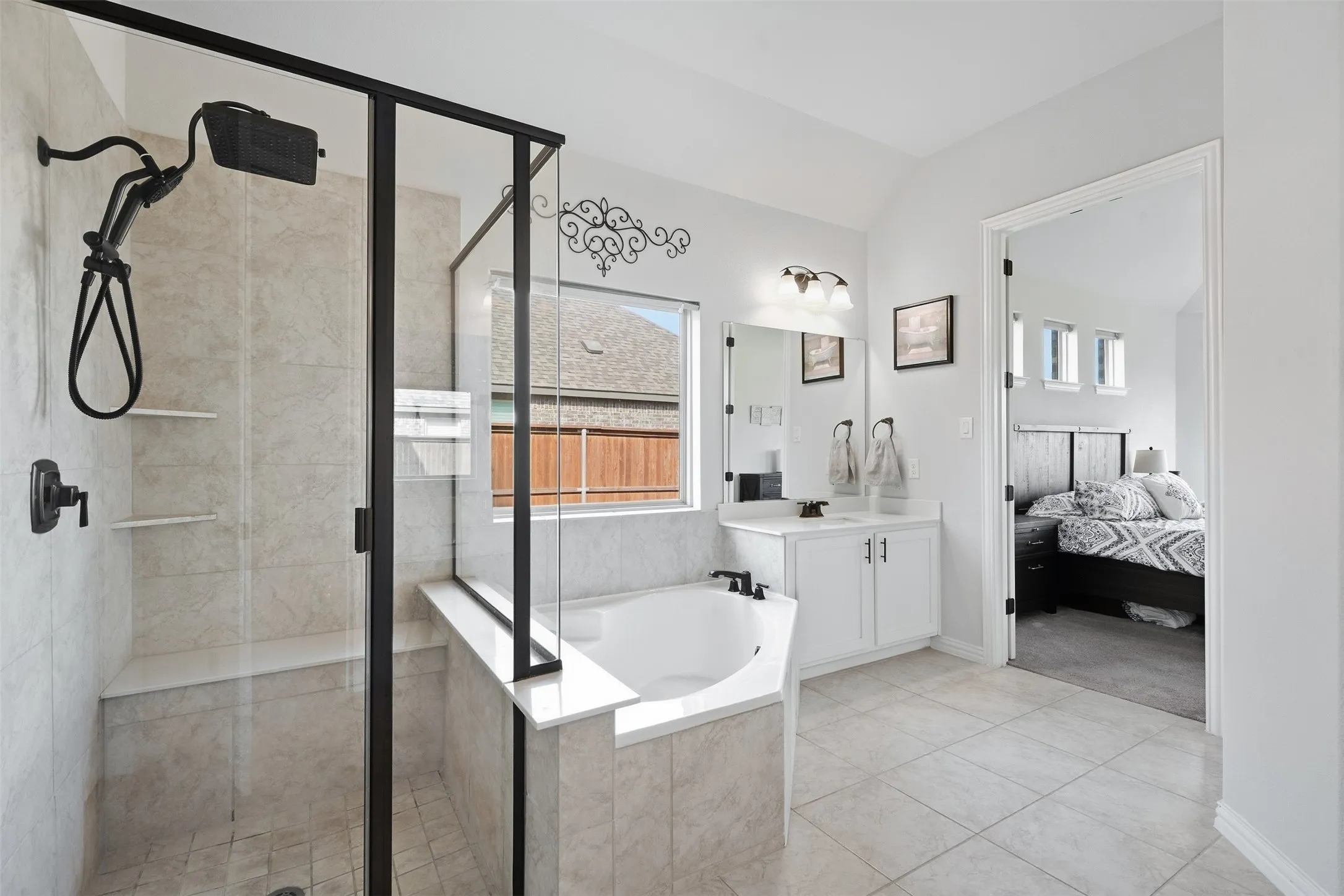Shower enclosure with black framing and built-in bench, corner soaking tub, single vanity with white cabinetry, wall-mounted light fixture, and tiled flooring
