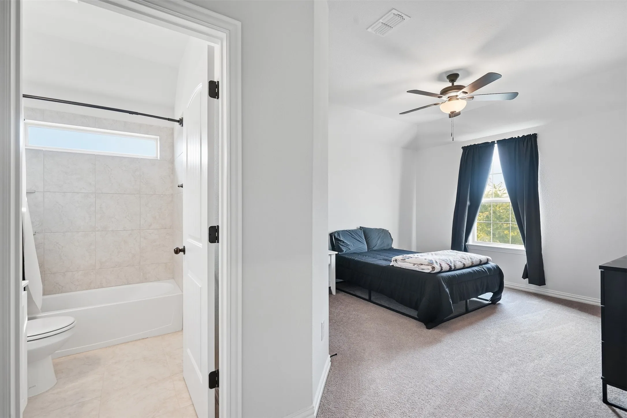 Bedroom with vaulted ceiling, ceiling fan, and carpet flooring