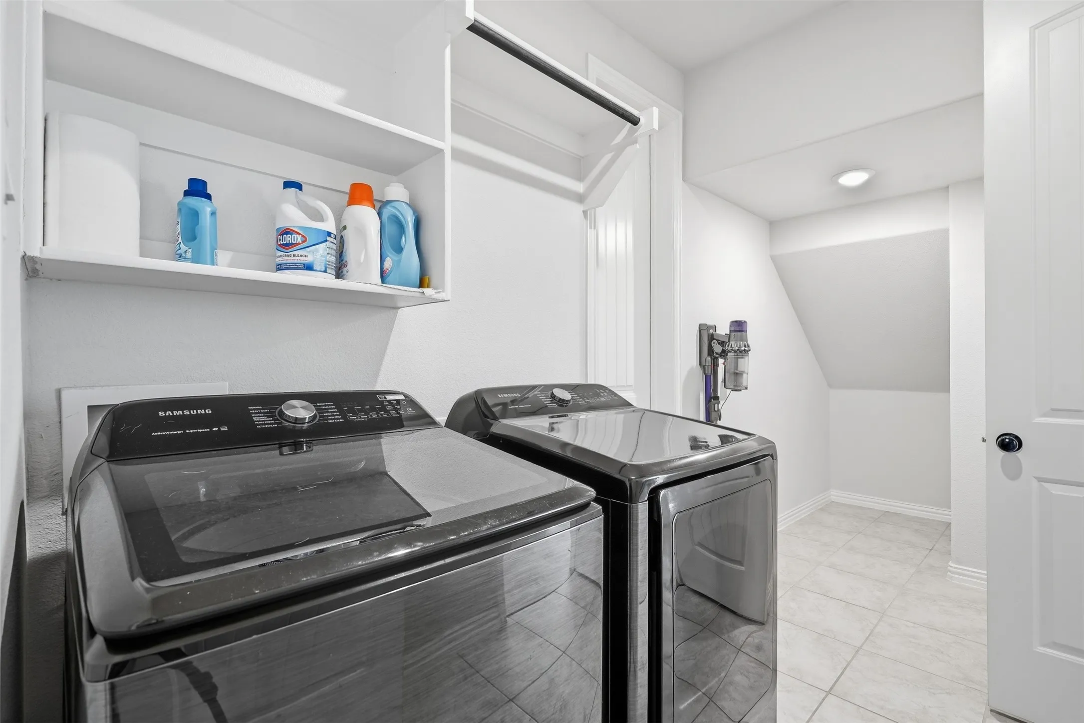 Laundry area with tile flooring, built-in shelving, and a hanging rod