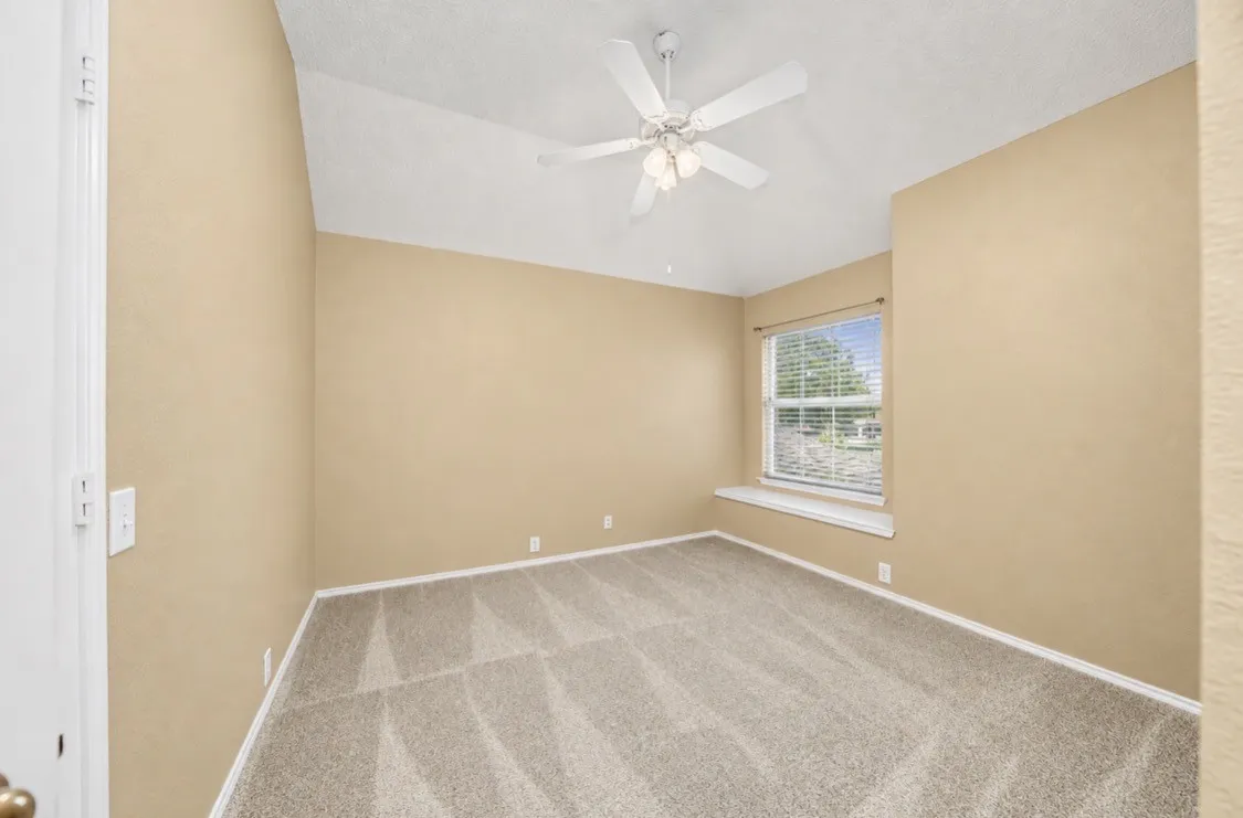 Vaulted ceiling with a ceiling fan, neutral carpet flooring, and a single window with blinds