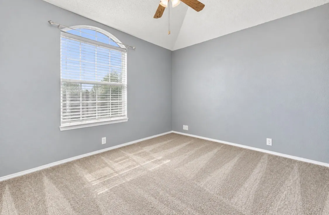Arched window with blinds, ceiling fan, and sloped ceiling