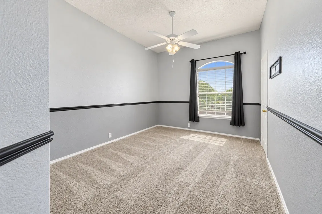 Vaulted ceiling with a ceiling fan, arched window, and carpeted flooring